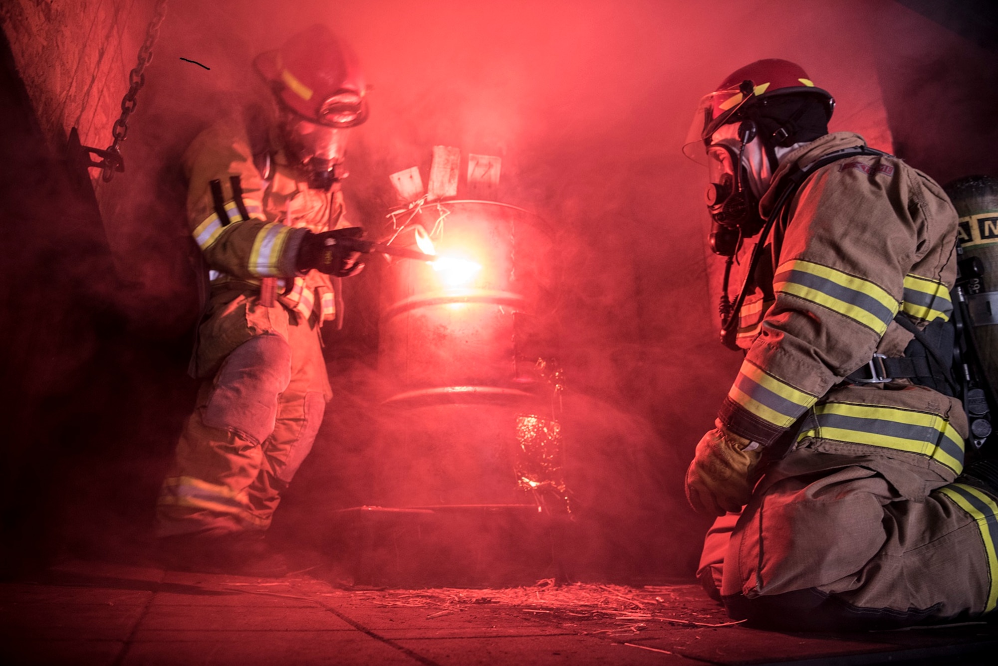 CHEYENNE MOUNTAIN AIR FORCE STATION, Colo. – Instructors from the Colorado Springs Fire Department training division use a road flare to light a fire during flashover training at the Cheyenne Mountain Air Force Station, Colo., fire training area, June, 9, 2017. Flashover training is integral to becoming a firefighter as it it gives a firefighter a front row seat to the behavior of fire in an enclosed space. (U.S. Air Force photo by Steve Kotecki)