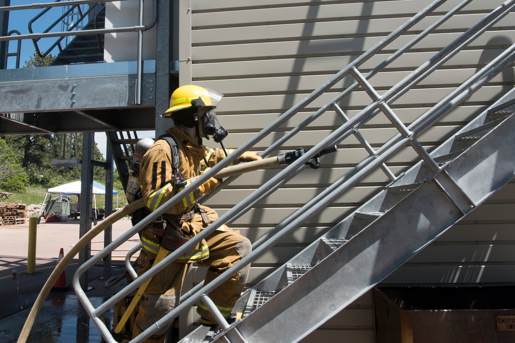 CHEYENNE MOUNTAIN AIR FORCE STATION, Colo. – A recruit from the Colorado Springs Fire Department training division carries hose up a flight of steps while training at the Cheyenne Mountain Air Force Station, Colo., fire training area, June, 9, 2017. The three-story building allows for a multitude of firefighting and rescue operations. (U.S. Air Force photo by Steve Kotecki)