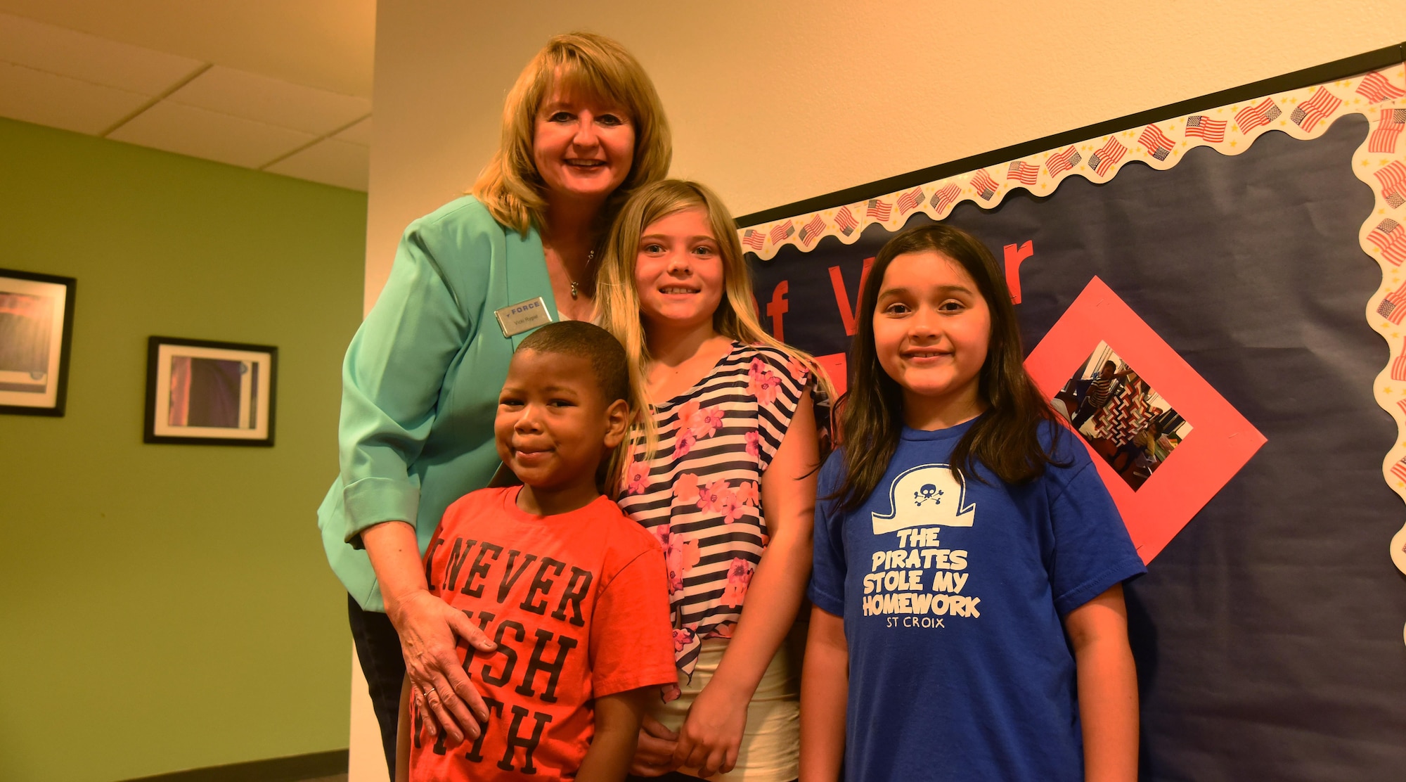 Vicki Rygiel, 21st Force Support Squadron School Age Care program coordinator, smiles with Christian Smithwick, Coady Sellers and Emma Mosley, SAC program children, inside the R.P. Lee Youth Center at Peterson Air Force Base, Colorado, Monday, June 12, 2017. Rygiel earned the Air Force Civilian Specialist of the Year award in recognition of her service with Schriever’s SAC program. (U.S. Air Force photo/Airman 1st Class William Tracy)