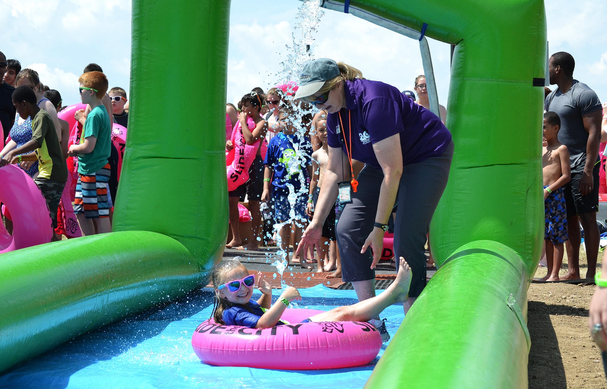 Vicki Rygiel, former Schriever School Age Care program coordinator, gives Zoey Boone a push down the giant slip-and-slide during Slide the City at Schriever Air Force Base, Colorado, Aug. 19, 2016. During her more than three years at Schriever, Rygiel participated in and organized many events to help kids learn and have fun on base, earning her Air Force level recognition. (U.S. Air Force photo/Brian Hagberg)