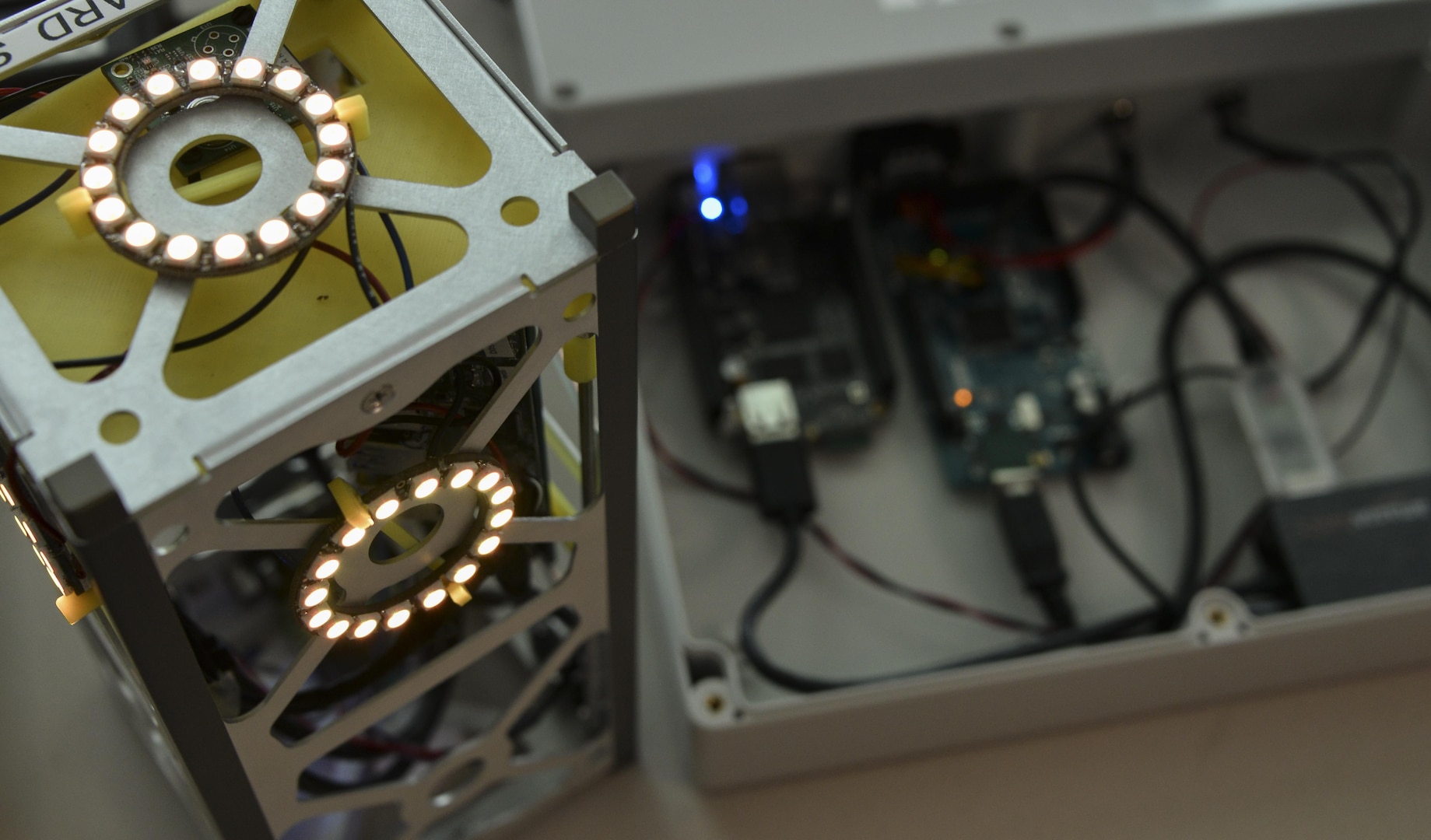 The glowing LED lights on a miniature satellite, or CubeSat, simulate thrusters firing while the satellite is connecting to a ground station during the Space Cyber Challenge May 22, 2017, in Linthicum Heights, Maryland. Five 707th CS Airmen, alongside NSA personnel and NASA engineers, competed against graduate students from the Royal Military College of Canada during the challenge. (U.S. Air Force photo/Staff Sgt. Alexandre Montes) 