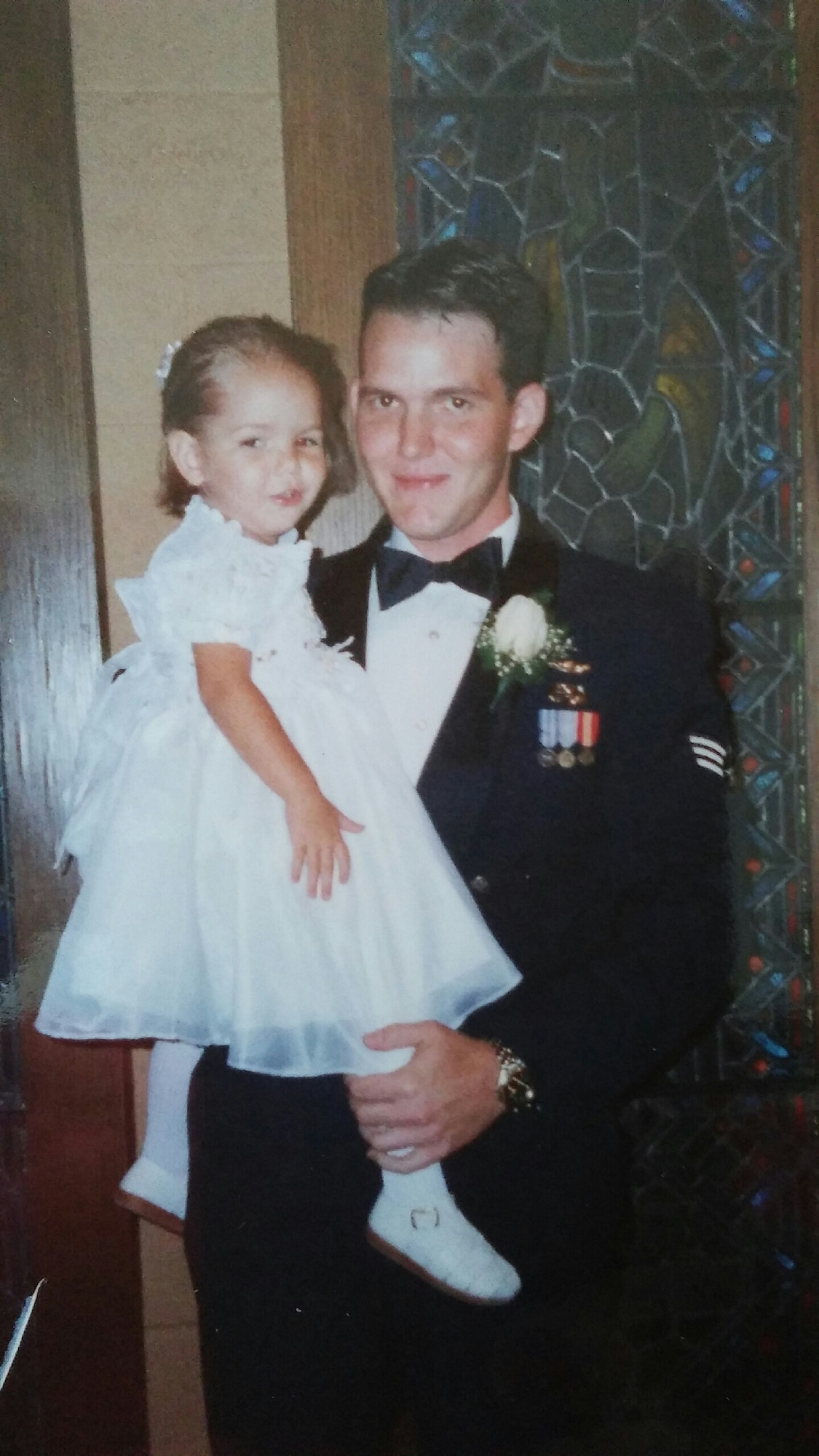 3-year-old Gabrielle Honeycutt, now an Airman Basic and radiology trainee with the 60th Diagnostics and Therapeutics Squadron at David Grant USAF Medical Center, poses with her father, now-Senior Master Sgt. Jerry Honeycutt, 60th Operations Support Squadron, at a wedding in 1999. Father and daughter are both stationed at Travis and are enjoying time together before Airman Honeycutt moves to Joint Base Langley-Eustis, Virginia, to serve at her first duty station. (U.S. Air Force photo / 2nd Lt. Sarah Johnson)
