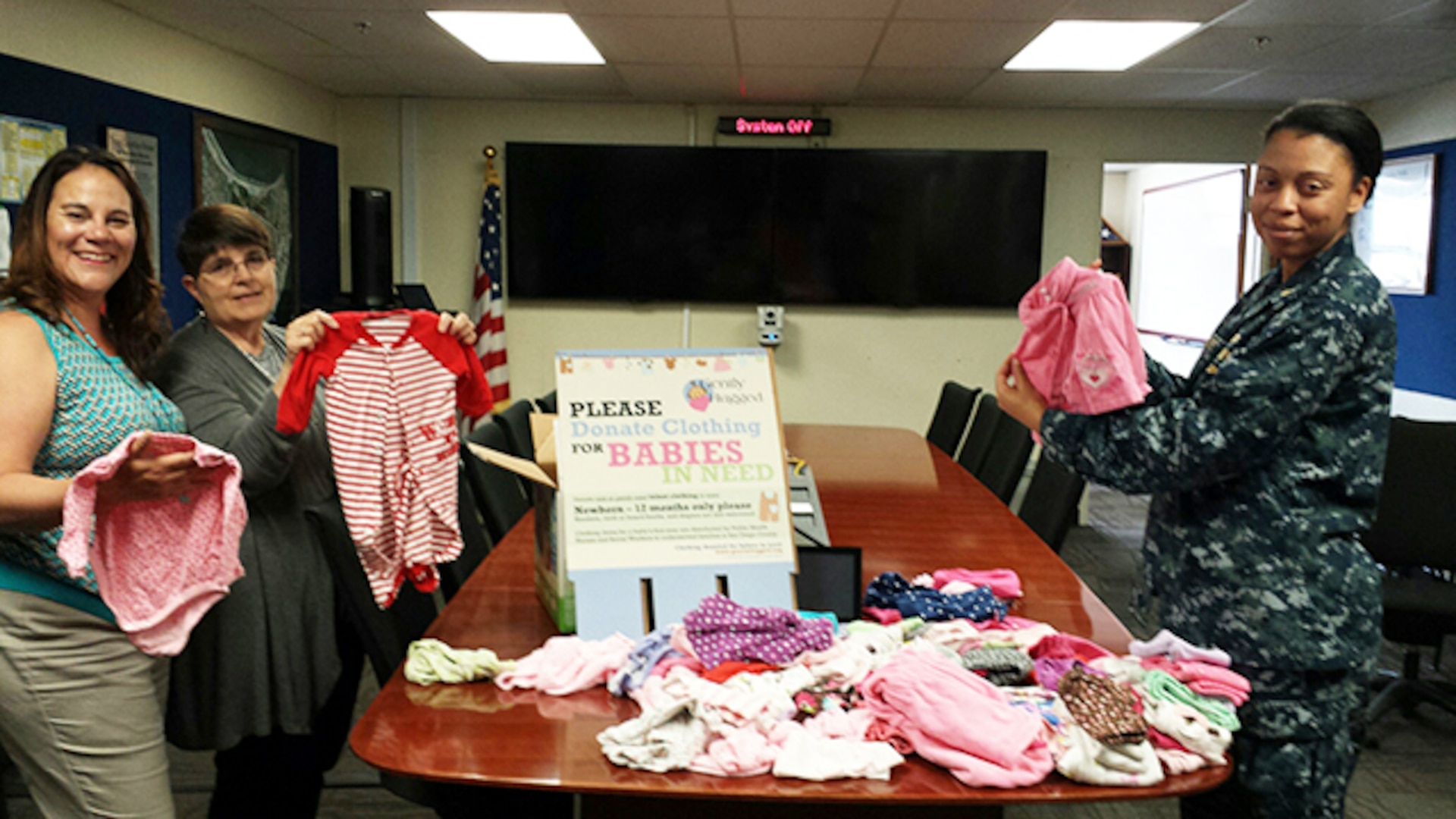 Defense Logistics Agency Aviation-San Diego employees Navy Lieutenant Junior Grade Angeli Legardye, right, Contract Specialist Nicole Johnson, left, and Management Analyst Karen Higdon, middle, sort through clothing donated by employees for local non-profit organizations to distribute to families in need. The program collects clothing for newborn to 1 year-old children of families who have been identified by local nurses and social service agencies.