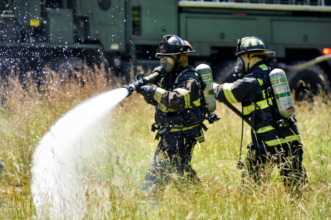 North Carolina Army and Air National Guardsmen use a fire hose to extinguish a simulated crash fire during exercise Operation Vigilant Catamount in Dupont State Forest, Hendersonville, N.C., June 8, 2017. Operation Vigilant Catamount is a joint civilian and National Guard regional domestic operations and homeland security exercise. Army National Guard photo by Staff Sgt. David McLean