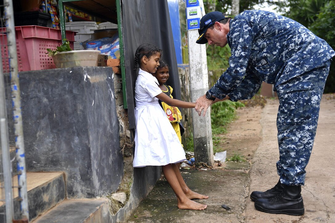 Navy Capt. Darren McPherson, commanding officer of the USS Lake Erie, shows Sri Lankan children how to "low-five" in Colombo, Sri Lanka, June 12, 2017. The USS Lake Erie arrived in Sri Lanka to support humanitarian assistance operations in the wake of severe flooding and landslides that devastated many regions of the country. Navy photo by Petty Officer 3rd Class Lucas T. Hans