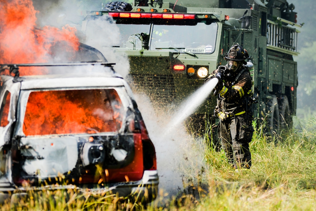 A guardsman extinguishes a fire at a simulated crash site during an exercise.
