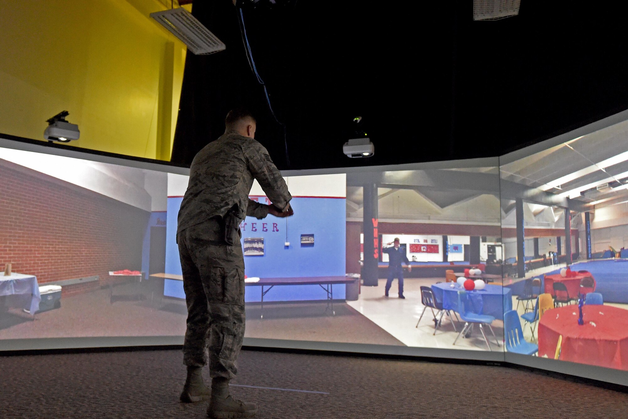 Air Force Staff Sgt. Jeffrey Travis, 673d Security Forces Squadron unit training instructor, unholsters his weapon during a simulated training exercise while demonstrating the capabilities of the Multiple Interactive Learning Objectives training system at Joint Base Elmendorf-Richardson, Alaska, June 8, 2017. The training system provides a myriad of training options which include dealing with active shooters, burglaries, domestic violence, emotionally disturbed individuals, and simulated patrols.