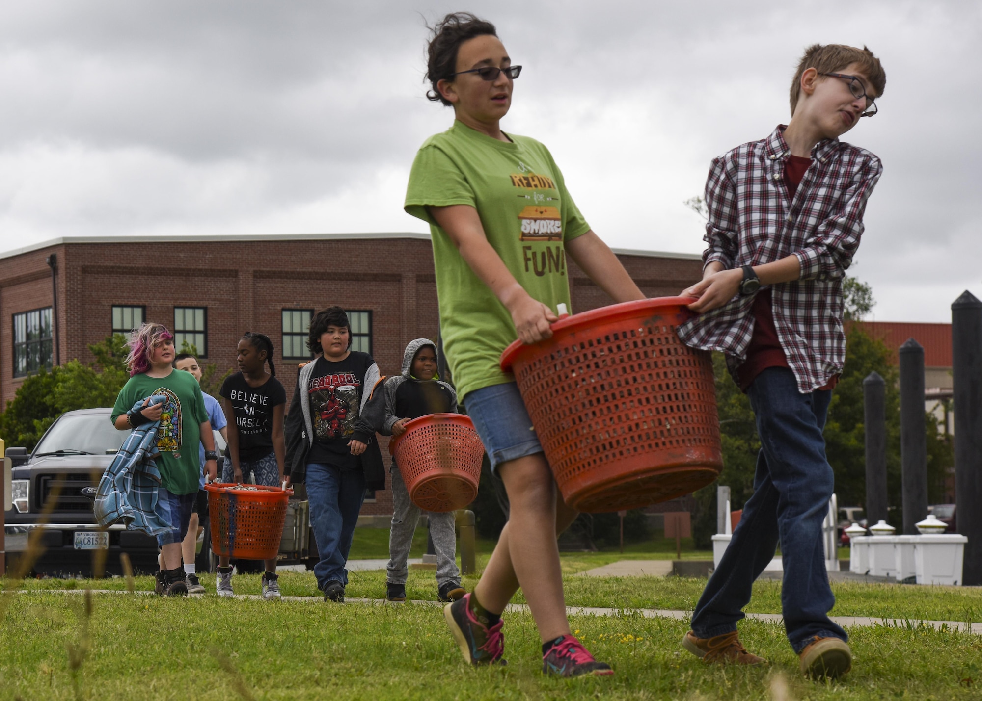Students from Booker Elementary Schoolcarry oyster bushels during an oyster planting event at Joint Base Langley-Eustis, Va., June 8, 2017. According to the National Oceanic Atmospheric Administration, degrading water quality is both a cause and an effect of the oyster decline, as fewer oysters result in less filtration capacity. (U.S. Air Force photo/Airman 1st Class Anthony Nin Leclerec)
