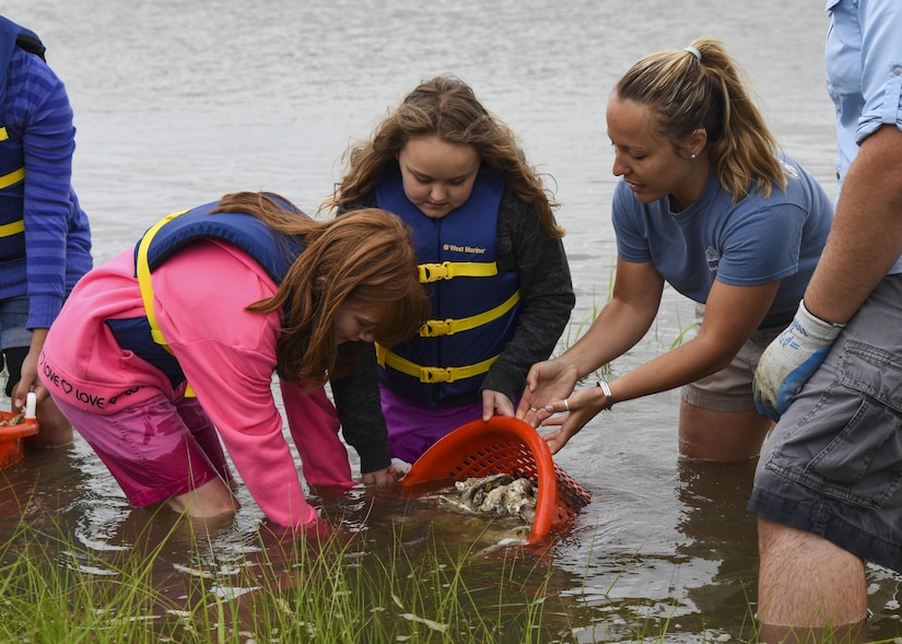 Heather North, Chesapeake Bay Foundation oyster restoration specialist, helps students from Booker Elementary School, Va., spread oysters during an oyster planting event at Joint Base Langley-Eustis, Va., June 8, 2017. The Booker Elementary School students planted 2,000 baby oysters onto the new reef to help increase water clarity with the oysters’ natural filtering capability. (U.S. Air Force photo/Airman 1st Class Anthony Nin Leclerec)