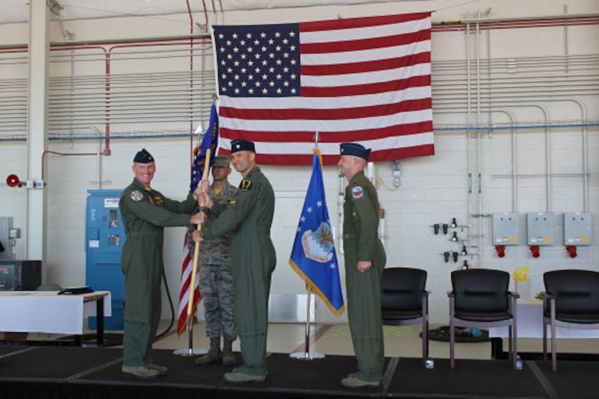 388th Fighter Wing Operations Group commander Col. Jason Rueschhoff hands the 4th Fighter Squadron guidon to new 4th Fighter Squadron commander Lt. Col. Yosef Morris at a ceremony June 9 at Hill Air Force Base as former commander Lt. Col. Steven Engberg stands at attention.