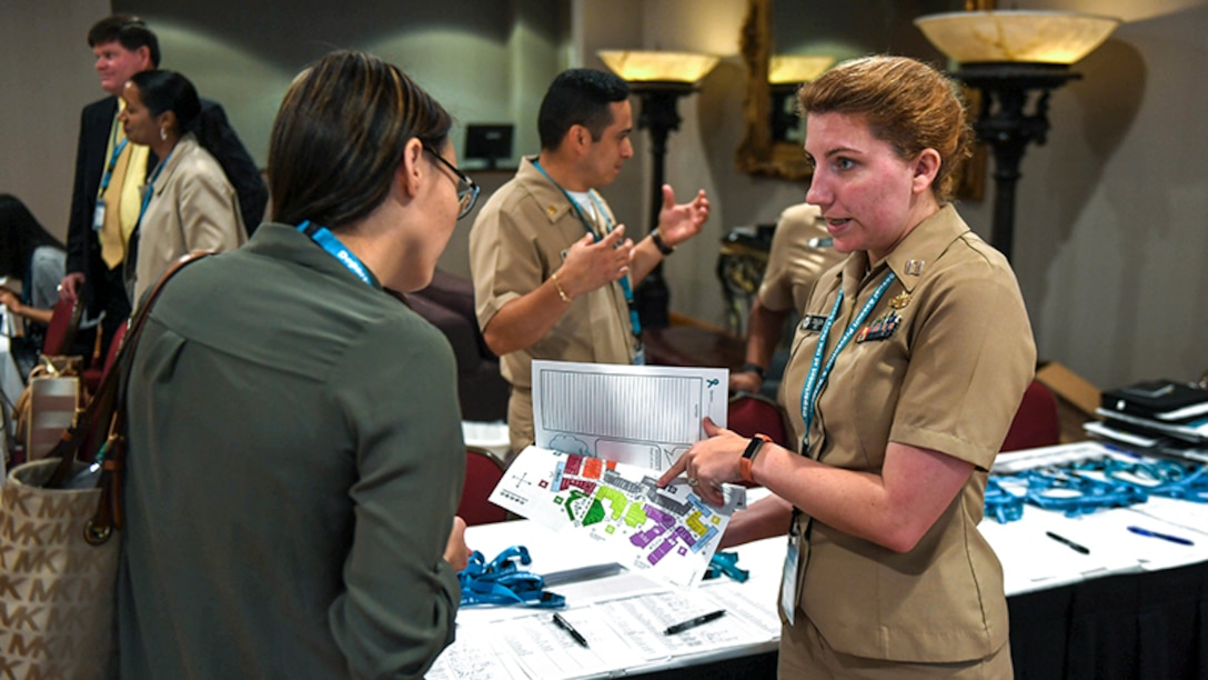 This image shows a female sailor helping a victim's advocate sign in at a Navy training seminar.