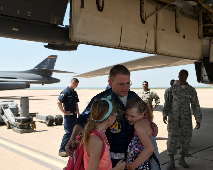 U.S. Air Force Tech. Sgt. Clayton Moore, 489th Maintenance Squadron weapons load crew member, is hugged by his daughters, Kaylin, left, and Jaydin during the 2017 Global Strike Challenge at Dyess Air Force Base, Texas, June 13, 2017. Moore’s children were given a rare opportunity to see him in action. (U.S. Air Force photo by Senior Airman Kedesha Pennant)