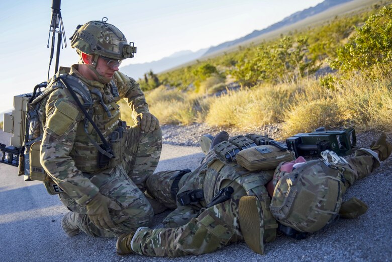 Senior Airman William Butler, 99th Civil Engineer Squadron explosive ordnance disposal technician, simulates tactical combat casualty care with Staff Sgt. Myles Corbin, 99 CES EOD technician, who suffered a lower limb wound at the Nevada Test and Training Range June 7, 2017. Tactical combat casualty care provides immediate aide in hazardous situations. (U.S. Air Force photo by Airman 1st Class Andrew D. Sarver/Released)