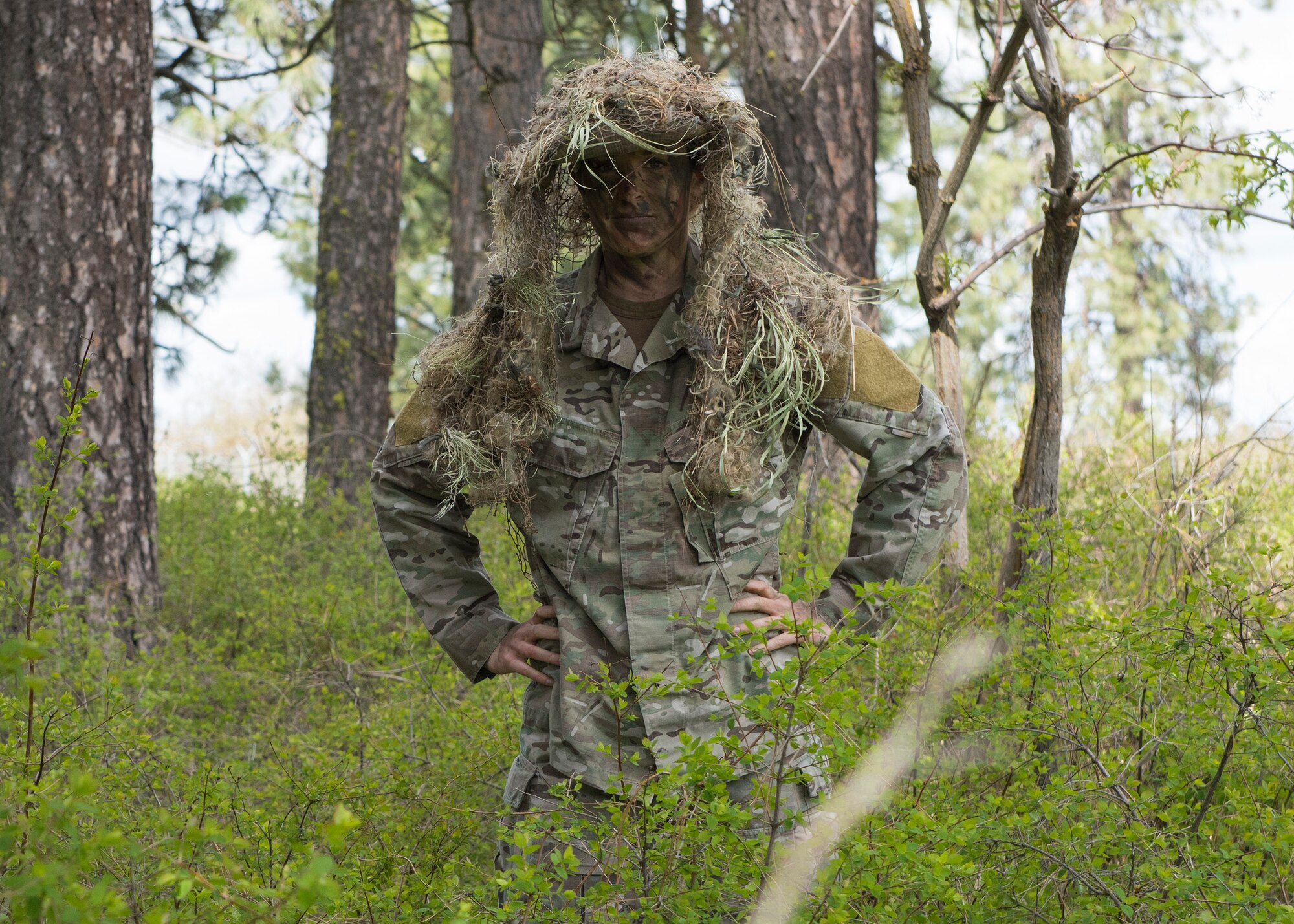 Senior Airman Brittany Wilson, 22nd Training Squadron survival specalist, reveals her location from under cover Apr. 28, Fairchild Air Force Base, Washington. Survival specalists go through six months of harsh training in order to become instructors. (U.S. Air Force Photo / Airman 1st Class Ryan Lackey)