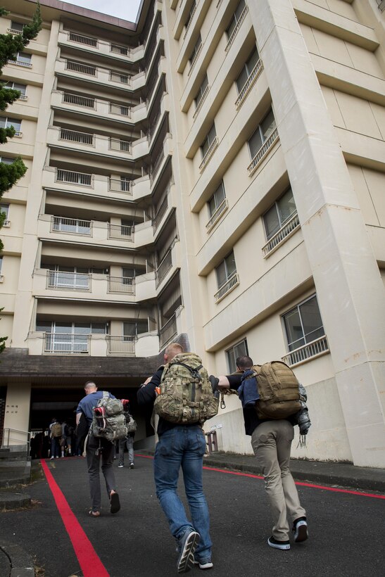 Noncombatant Evacuation Operations exercise participants walk into temporary housing, June 6, 2017, at Yokota Air Base, Japan. Most of the exercise participants were transported to Camp Zama while others stayed on Yokota Air Base in contingency quarters. (U.S. Air Force photo by Airman 1st Class Donald Hudson)