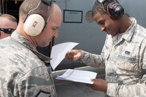 (Right to left) Airman 1st Class Braxton Ramsue, 730th Air Mobility Squadron passenger service agent, and Master Sgt. Victor Peterson, 730th Air Mobility Squadron passenger service superintendent, check passenger lists during noncombatant evacuation exercise Focused Passage 2017 at Yokota Air Base, Japan, June 6, 2017. FP 2017 is designed to ensure Eighth Army service members and families are prepared to evacuate during a crisis situation. (U.S. Air Force photo by Yasuo Osakabe/Released)