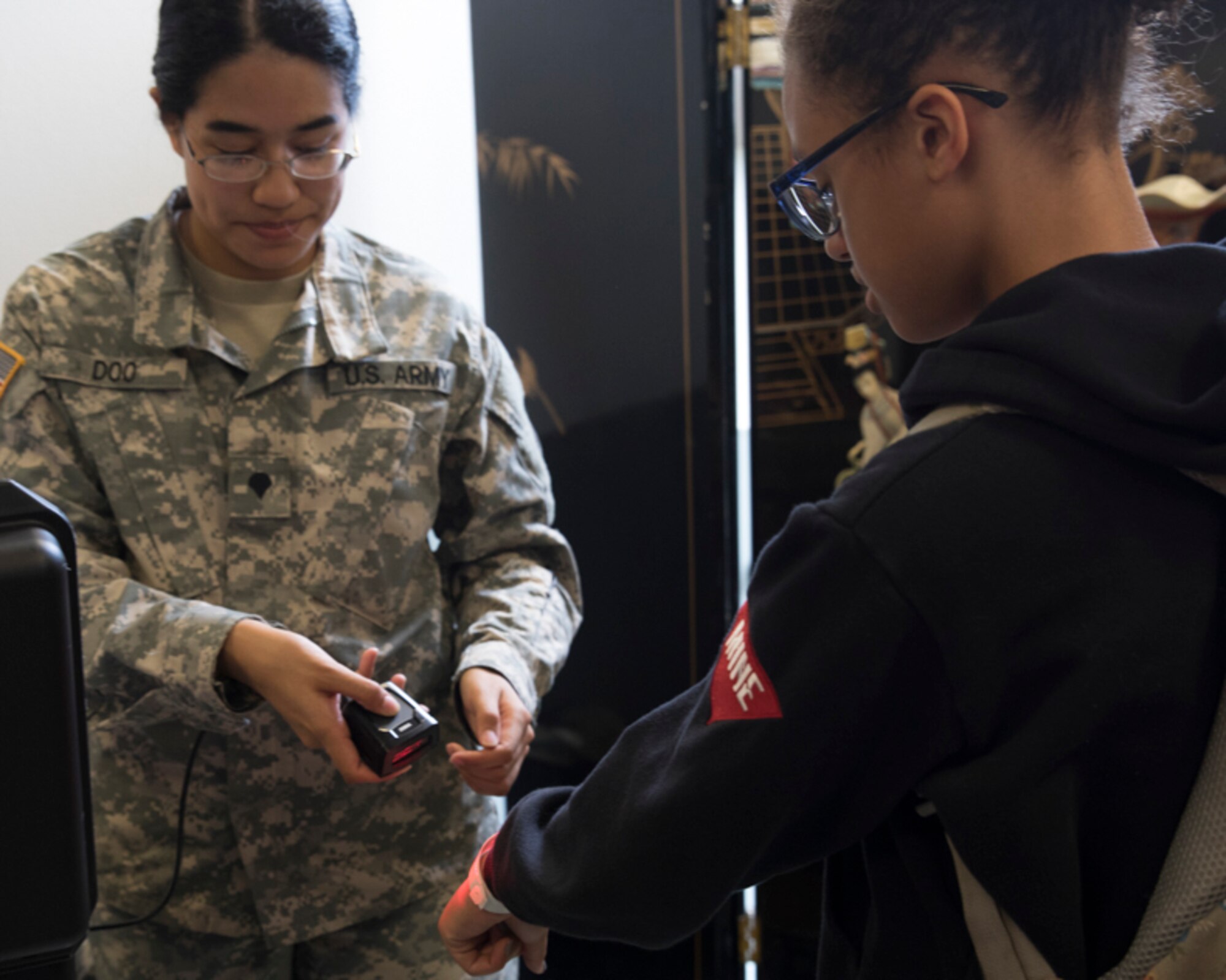 U.S. Army Specialist Brianna Doo, U.S. Army in Japan band, scans a bracelet with a Noncombatant Evacuation Operations tracking system (NTS) barcode at Yokota Air Base, Japan, during noncombatant evacuation exercise Focused Passage 2017. Eighth Army-Korea conducts NEO administrative and training tasks designed to inspect NEO packets, conduct NEO representative/warden training, NTS training, and account for all Department of Defense noncombatants. (U.S. Air Force photo by Yasuo Osakabe)