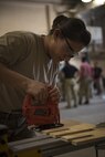 Staff Sgt. Janet Soto, 455th Expeditionary Logistics Readiness Squadron traffic management office, cuts a piece of wood at Bagram Airfield, Afghanistan, June 13, 2017. Soto created a weapon rack to hold various firearms. (U.S. Air Force photo by Staff Sgt. Benjamin Gonsier) 