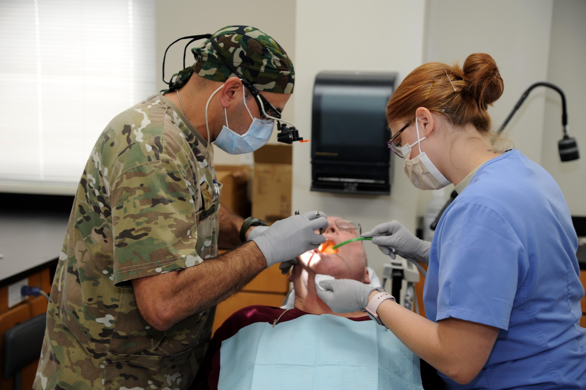 U.S. Army Maj. Jesus Morales, dentist, 49th Multifunctional Medical Battalion, Puerto Rico and U.S. Air Force Senior Airman Jessica Hawk, dental assistant, 172d Airlift Wing, Jackson Mississippi, extract a decayed tooth from Raymond Kline.  Kline participated in the no-cost medical services offered during the Ozark Highlands Innovated Readiness Training, Mountain Home, Arkansas, 5-12 June. (U.S. Air Force photo by Tech. Sgt. Peter Dean)  