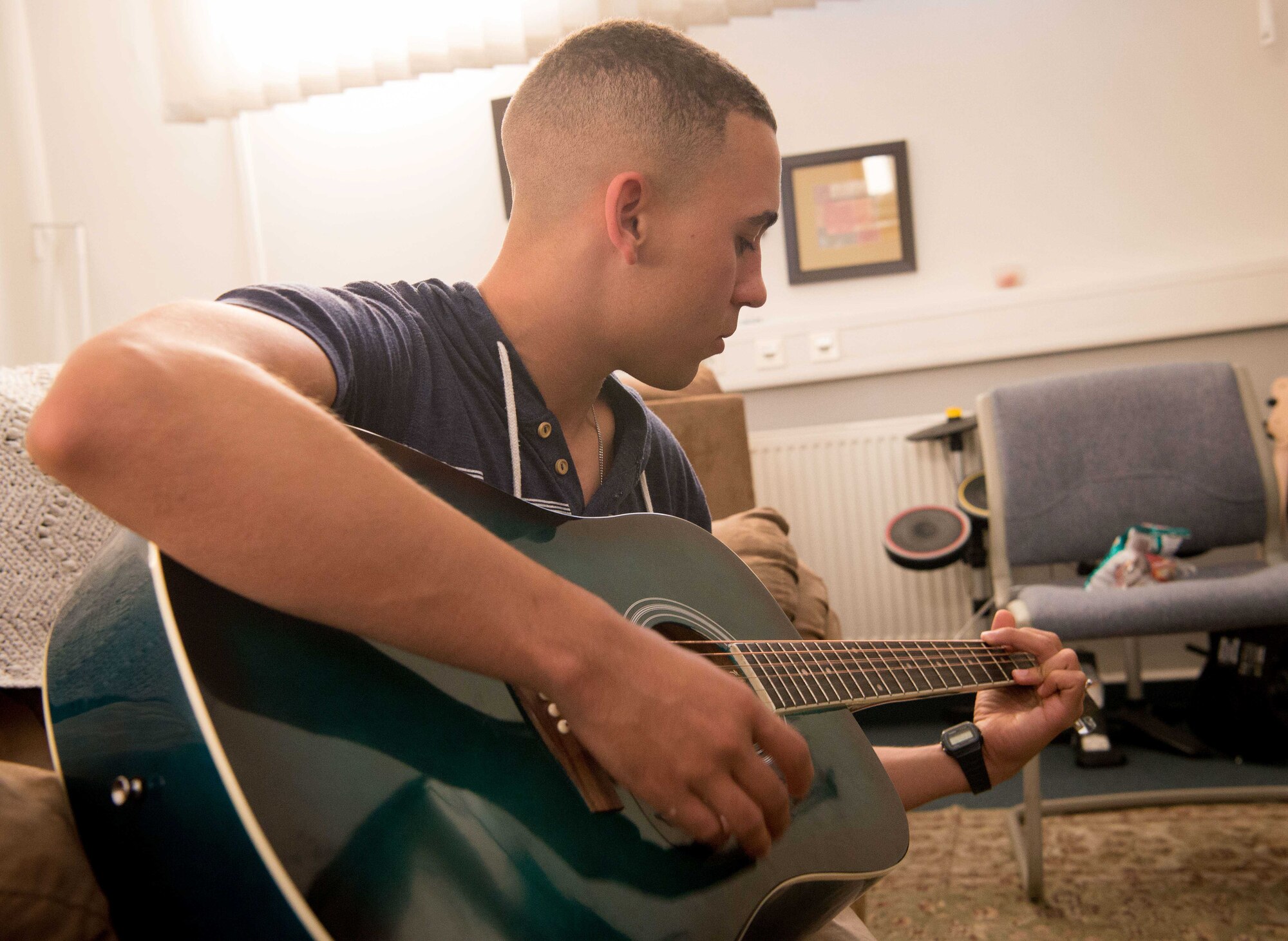 An Airman practices guitar in the music room at Club 7 on Ramstein Air Base, June 10, 2017. The Ramstein and Kapaun Air Station Club 7s have a number of facilities including music rooms, game rooms and movie rooms for junior enlisted Airmen to enjoy. (U.S. Air Force photo by Senior Airman Elizabeth Baker)
