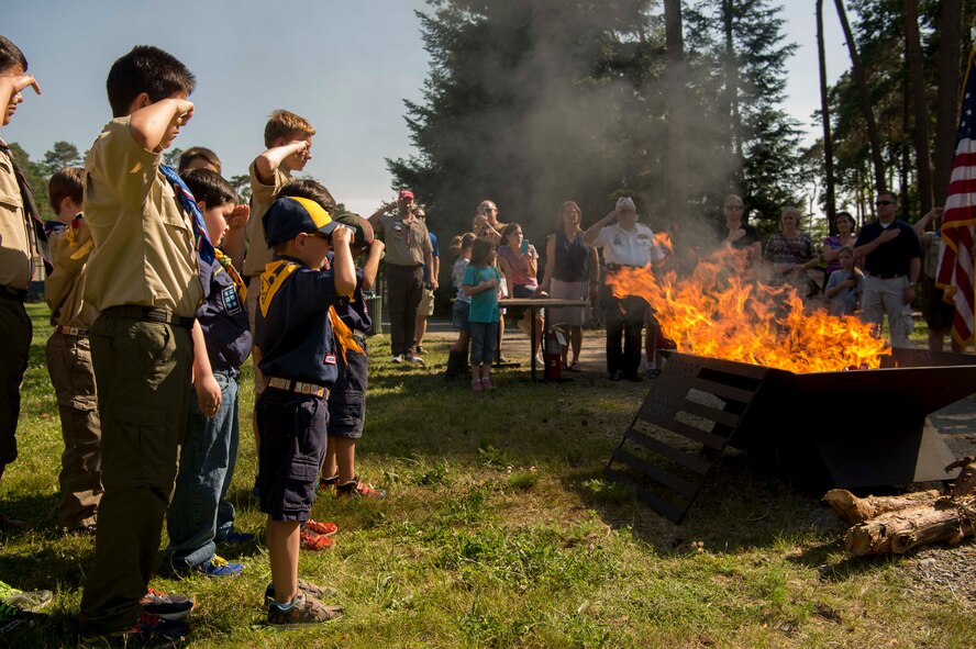 Children of Ramstein personnel who are members of the Boy Scouts of America and Cub Scouts of America salute burning U.S. flags during a Flag Day flag disposal ceremony on Ramstein Air Base, Germany, June 14, 2017. The scouts supported the ceremony to help make sure the flags were given proper respect during their disposal as defined by the United States Flag Code. (U.S. Air Force photo by Senior Airman Elizabeth Baker.)