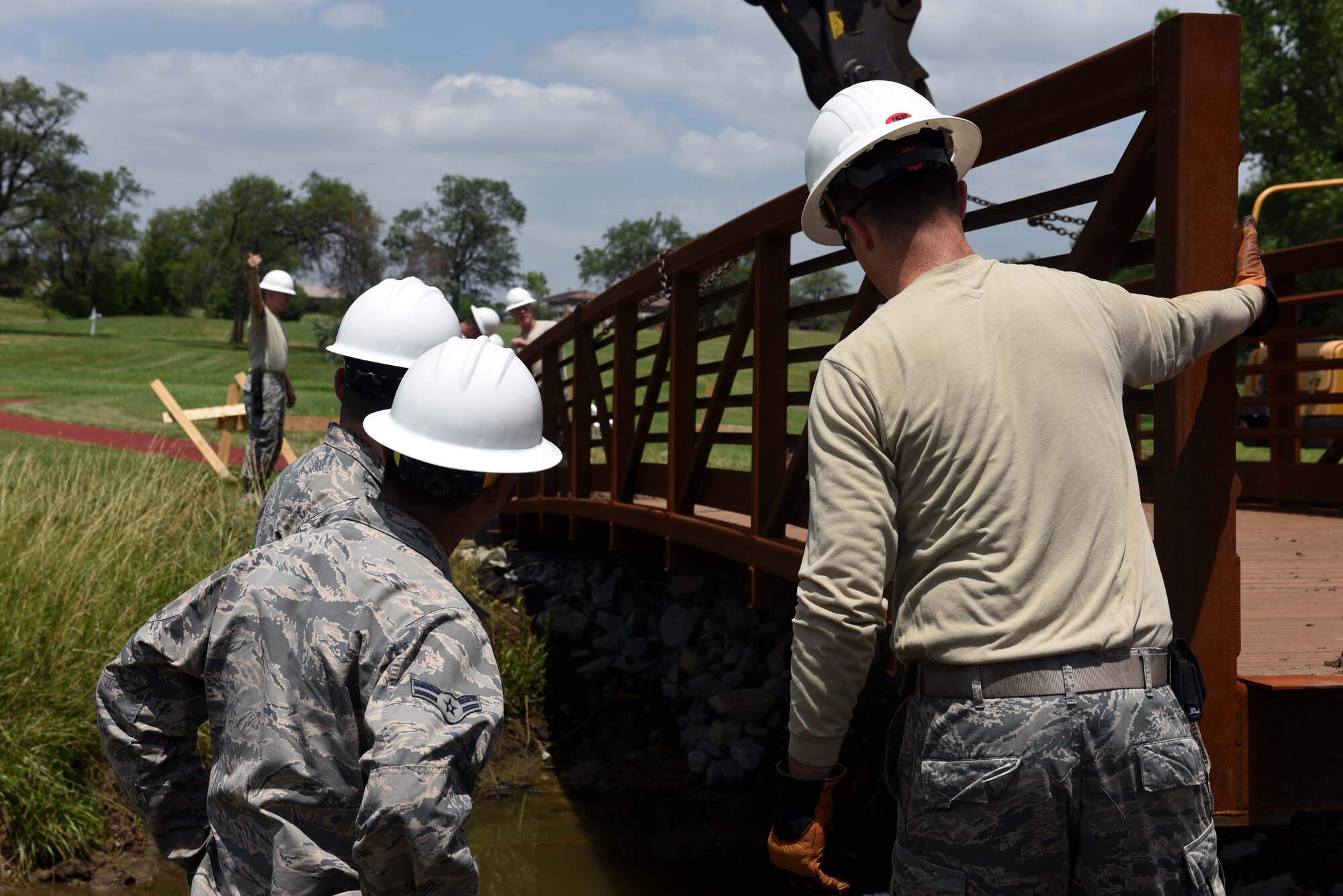 Twenty-second Civil Engineer Squadron Airmen redirect a bridge June 14, 2017 at the Kruger Recreational 2-mile track at McConnell Air Force Base, Kan. The 22nd CES replaced an older bridge that fell into the creek located on the track. (U.S. Air Force photo/Airman 1st Class Alan Ricker)