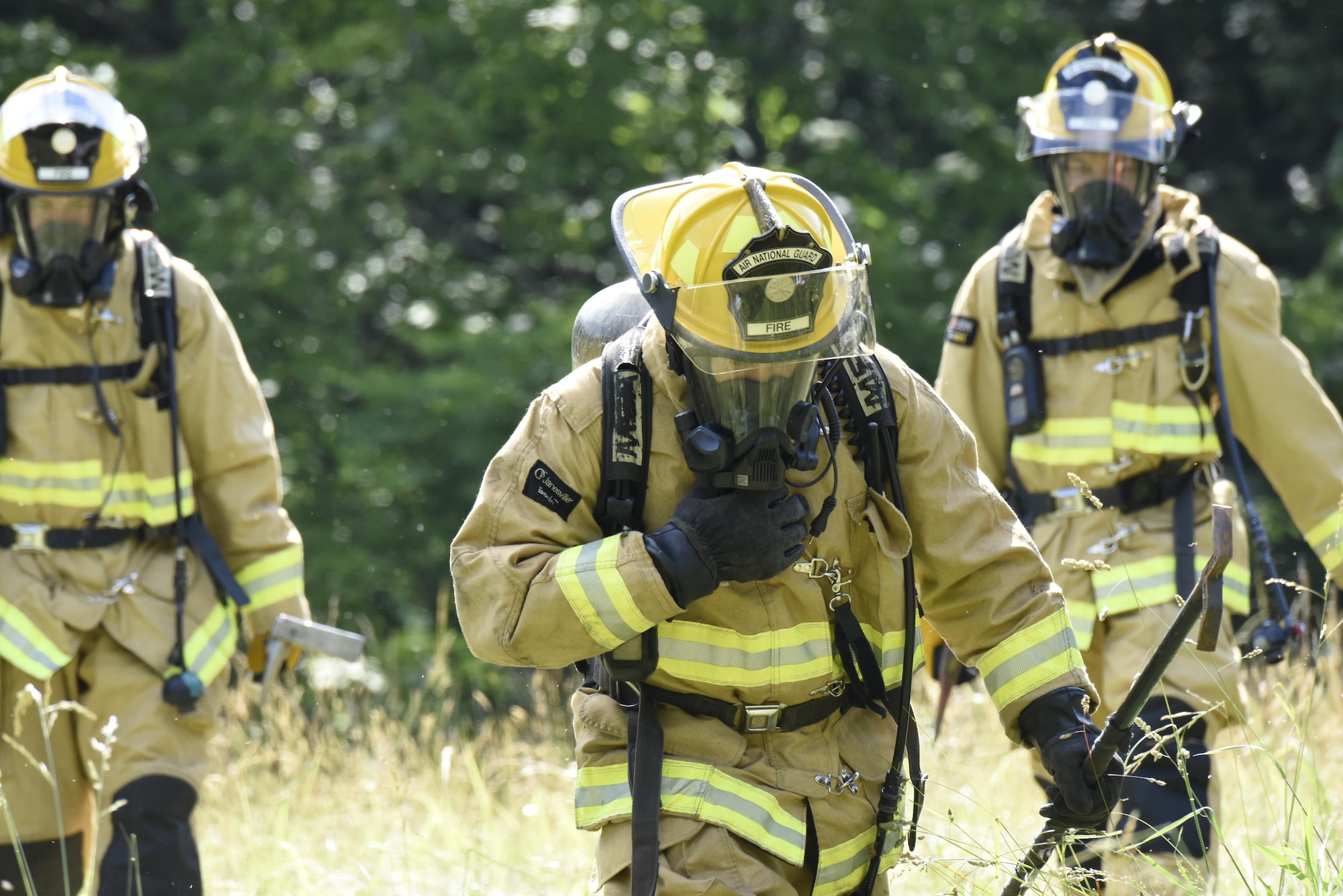 Three fire fighters with the North Carolina Nation Guard's Army and Air Force firefighting team walk away from the site of a simulated fire while at Vigilant Catamount, an interagency domestic exercise between local, state, and military personnel in North Carolina, at Dupont State Forest, Hendersonville North Carolina, June 8, 2017. Vigilant Catamount is a multi-day exercise testing emergency response, starting with the simulated crash of an F-15 aircraft. The fire fighters helped to extinguish two burning vehicles set ablaze to test military emergency firefighting capabilities.