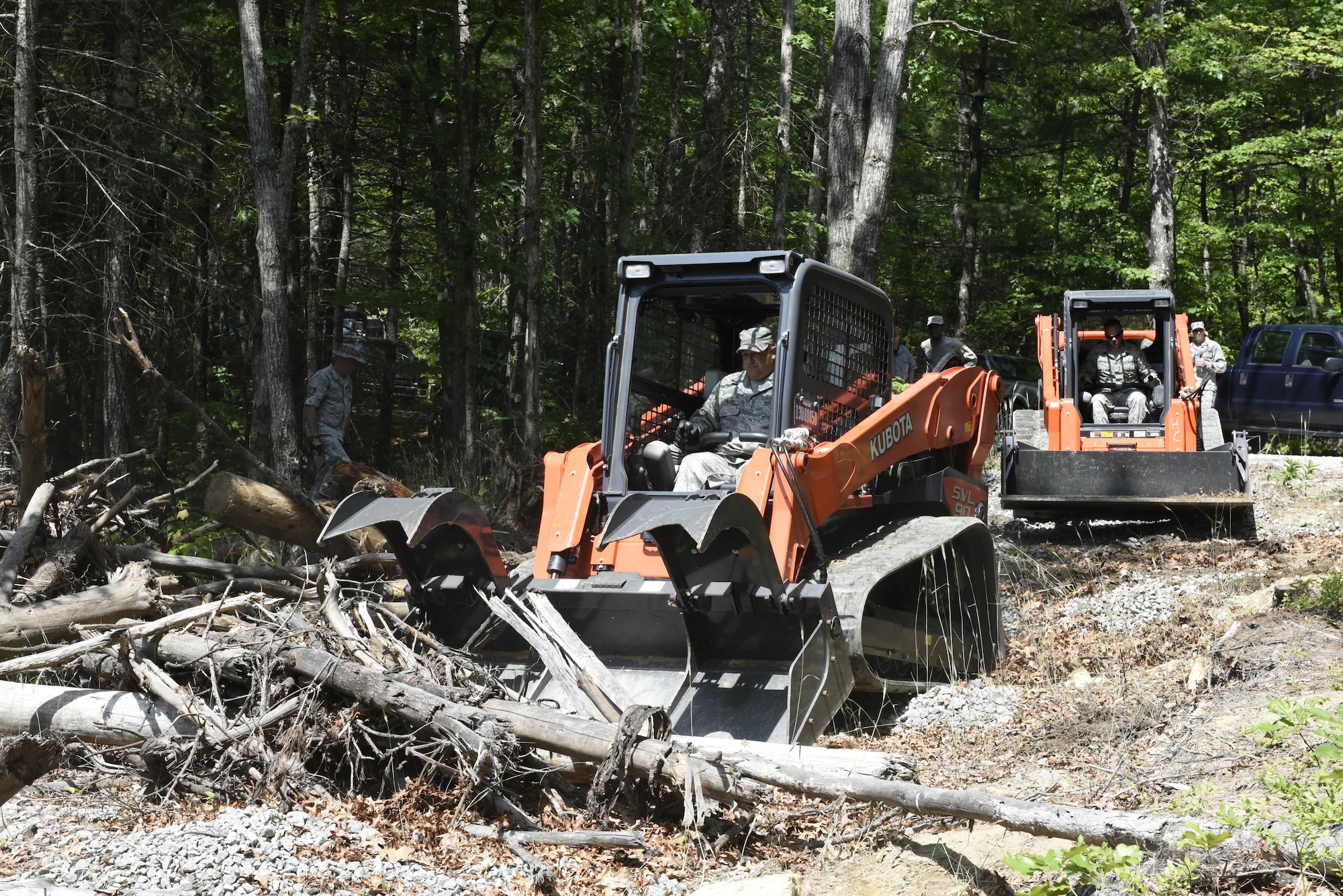 U.S. Air Force Staff Sgt. Adam Palmer (left) and Staff Sgt. Alan L. Zimmerman (right) heavy equipment operators with the 145th Airlift Wing Civil Engineer Squadron operate skid loaders to clear debris from a simulated F-15 crash site during Vigilant Catamount, an interagency domestic exercise between local, state, and military personnel in North Carolina, at Dupont State Forest, Hendersonville North Carolina, June 8, 2017. The skid loader is a part of the debris package unit that is utilized during disasters to open blocked roadways and allow emergency response personnel to reach injured victims during a disaster.