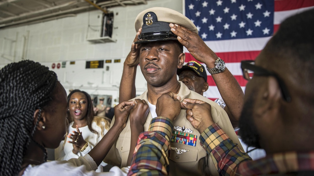 A sailor's family members participate in a ceremony promoting him to the rank of senior chief petty officer.