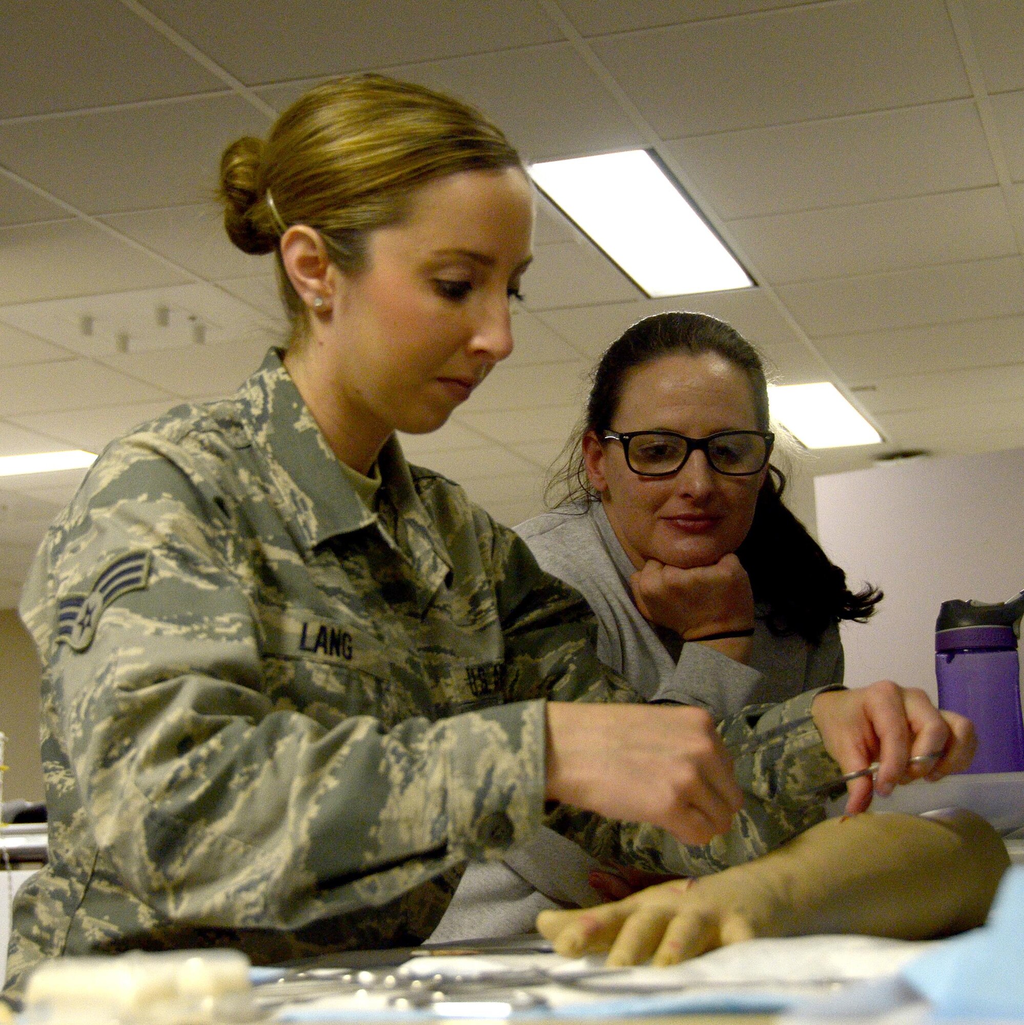Senior Airman Jessica Lang, an aerospace medical technician with the 445th Aerospace Medicine Squadron, practices wound suturing while Senior Airman Kelsey Rayburn watches her at the Wright-Patterson Air Force Base Medical Center, May 7, 2017. The Airmen received the chance to hone their sewing skills at the suturing station during training held during the unit training assembly. (U.S. Air Force photo/Staff Sgt. Joel McCullough)