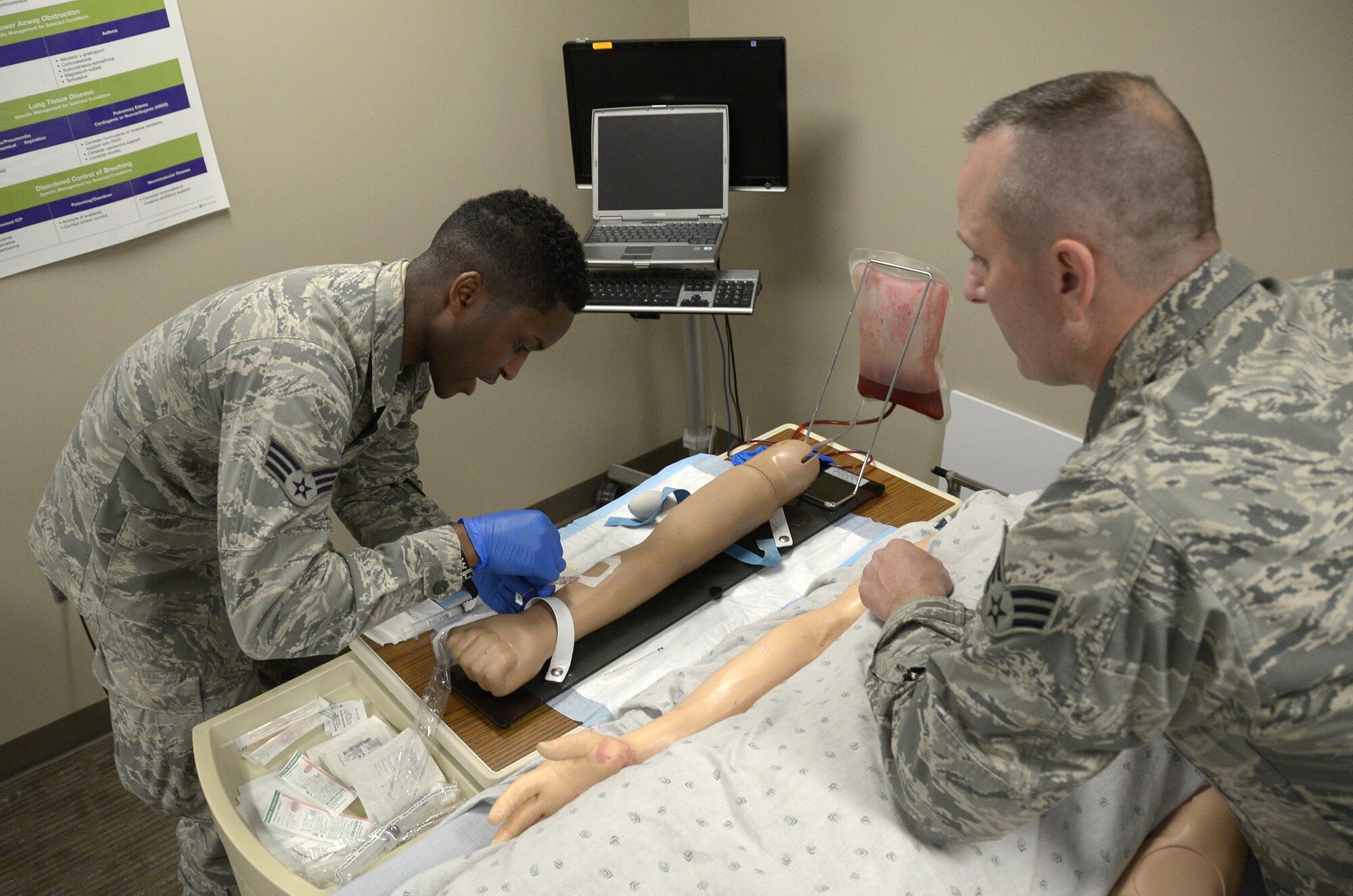 445th Aerospace Medicine Squadron medical technician Senior Airmen Michael Bell watches fellow AMDS aerospace medical technician Senior Airman Lorenzo Hines as he practices placing an Intravenous (IV) needle into a patient’s arm during the May 7, 2017 unit training assembly at the Wright-Patterson Air Force Base Medical Center. Bell ensured the Airmen participating in the training followed all proper techniques. (U.S. Air Force photo/Staff Sgt. Joel McCullough)