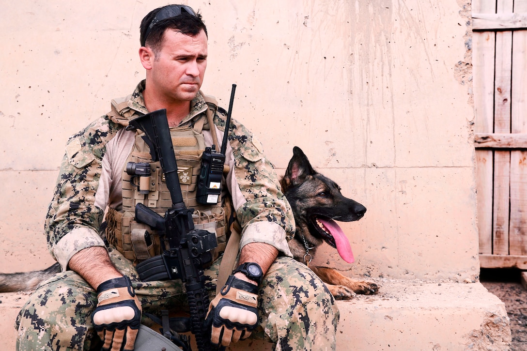 Navy Petty Officer 2nd Class Victor Green and his dog, Koko, a military working dog, take a break after a improvised explosive devices detection training at Camp Lemonnier, Djibouti, June 9, 2017. Green is a military working dog handler assigned to Combined Joint Task Force-Horn of Africa. Air Force photo by Staff Sgt. Lindsay Cryer
