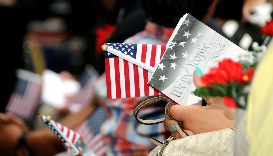 People hold U.S. flags June 14 prior to the start of a naturalization ceremony at the Betsy Ross House in downtown Philadelphia.  Maj. Gen. Troy D. Kok, commanding general of the U.S. Army Reserve’s 99th Regional Support Command, and retired Gen. Carter F. Ham, president and CEO of the Association of the United States Army and former commander of U.S. Africa Command, spoke at the event in which 13 individuals became U.S. citizens.