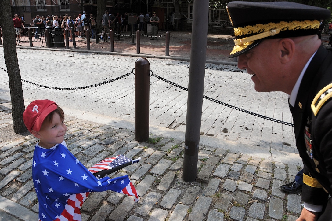 Maj. Gen. Troy D. Kok, commanding general of the U.S. Army Reserve’s 99th Regional Support Command, greets a small child wearing an American flag prior to the start of the Stripes and Stars Festival celebrating the U.S. Army 242nd birthday at Independence Hall in Philadelphia.
