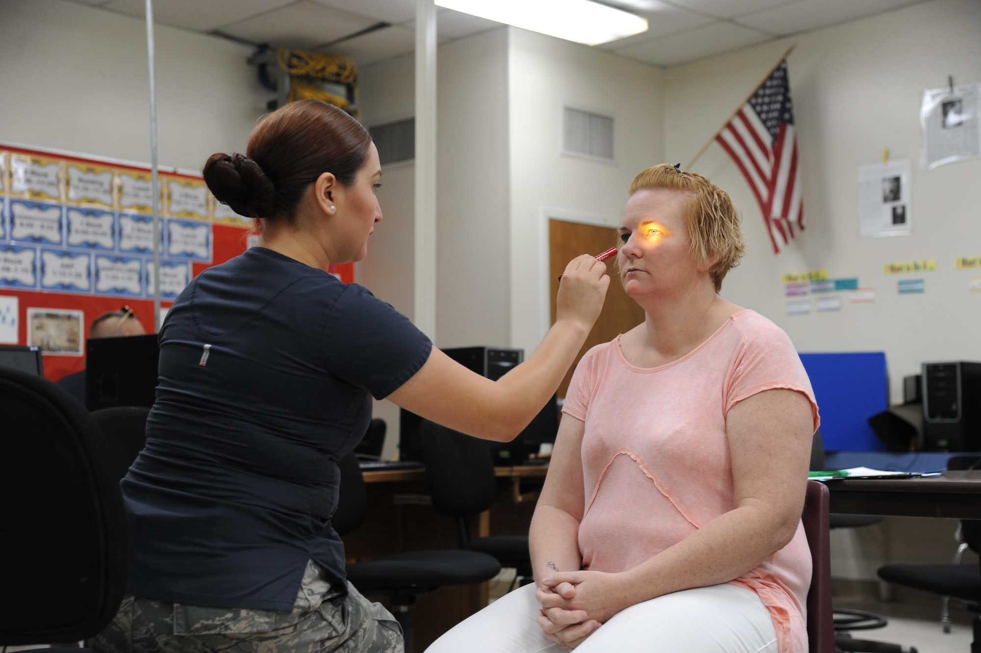 U.S. Air Force Staff Sgt. Christine Narro, optometry technician, 433rd Aeromedical Squadron, Joint Base San Antonio, Lackland Air Force Base, exams Trisha Diaz’s pupils during an eye exam. Diaz participated in the no-cost medical services offered during the Ozark Highlands Innovated Readiness Training, Mountain Home, Arkansas, 5-12 June. (U.S. Air Force photo by Tech. Sgt. Peter Dean)  