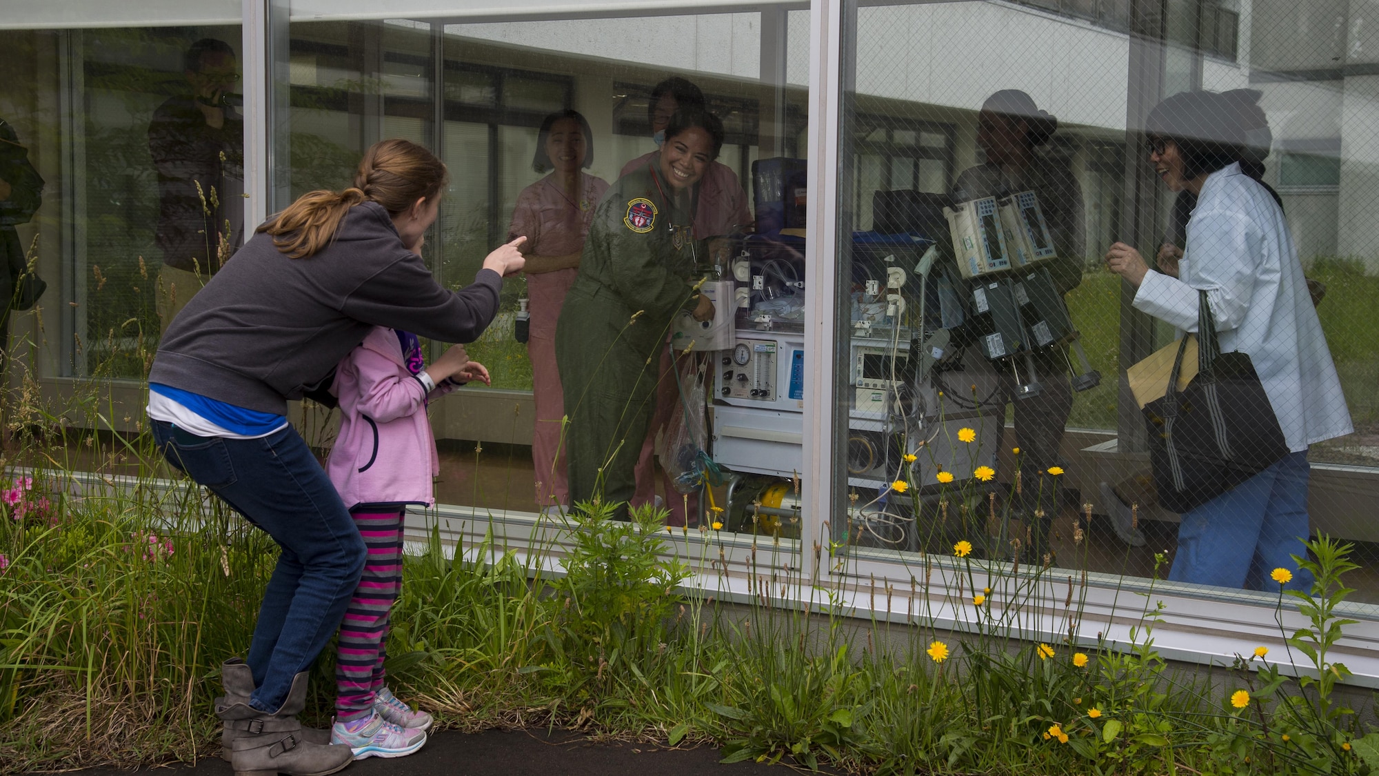 Katherine and Emmeline McKeown, spouse and daughter of U.S. Air Force Capt. Connor McKeown, waves to Oliver McKeown through the Aomori Hospital window prior to the aeromedical evacuation in Aomori, Japan, June 16, 2017. For Emmeline, this was the first time seeing her brother. Once the neonatal intensive care unit team from the U.S. Navy hospital, Okinawa, Japan, prepared Oliver for the flight, they transferred him to the Aomori Airport for departure. (U.S. Air Force photo by Senior Airman Deana Heitzman)