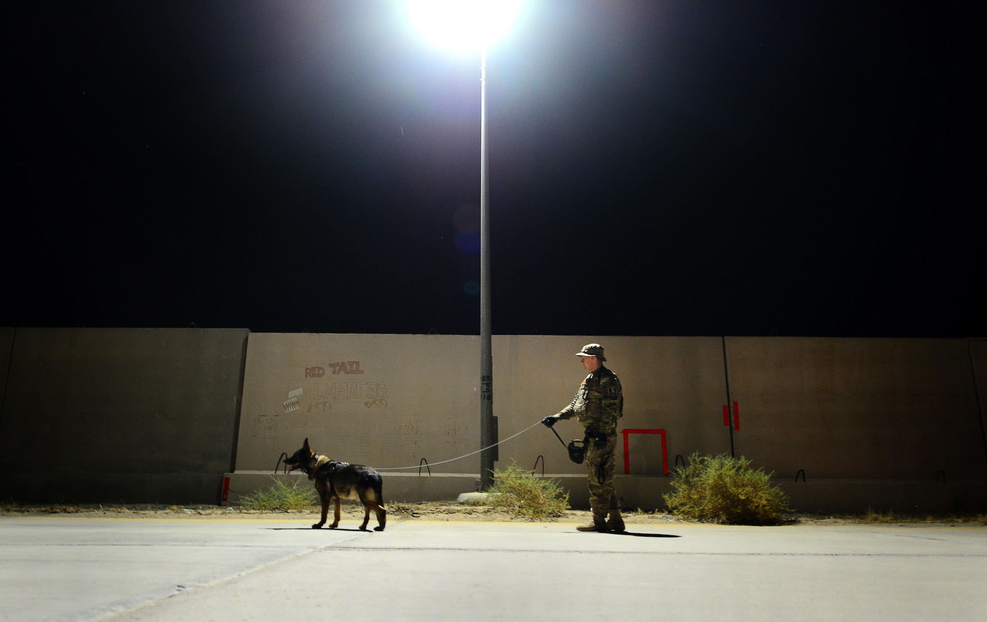 U.S. Air Force Senior Airman Carlton Isaacson, a military working dog handler assigned to the 407th Expeditionary Security Forces Squadron and his partner Egon, patrol the flightline in Southwest Asia on May 23, 2017. Isaacson and Egon have been partners for two years now and are deployed in support of Operation Inherent Resolve. Military working dogs are the first line of defense when it comes to explosive detection and provide security sweeps throughout the installation. (U.S. Air Force photo by Tech Sgt. Andy M. Kin)
