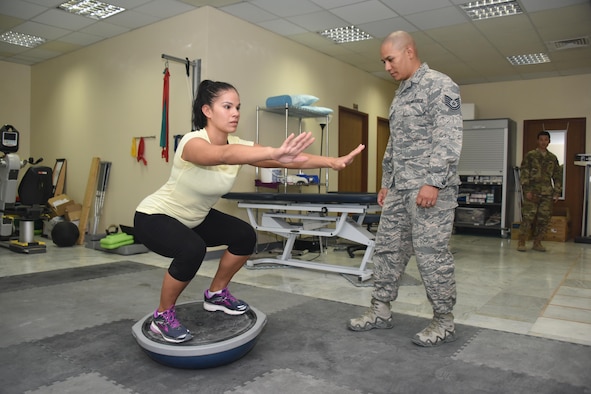 Tech. Sgt. David Garcia (middle), the NCOIC of physical therapy, 386th Expeditionary Medical Group, monitors the form of Staff Sgt. Melanie Hernandez, a patient with the 386th EMDG physical therapy clinic, as she performs squats on a stability ball during a physical therapy session at an undisclosed location in Southwest Asia, June 11, 2017. The physical therapy clinic provides an array of rehabilitative services to promote movement, reduce pain, restore function and prevent disability of injured military personnel. (U.S. Air Force photo/ Tech. Sgt. Jonathan Hehnly)