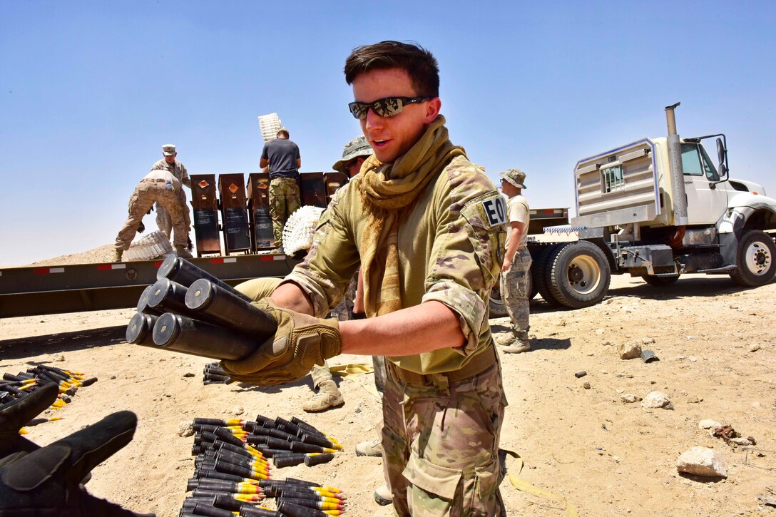 Air Force Senior Airman Kevin Oserguera passes munitions to another service member to unload a trailer during an explosive ordnance disposal operation in Southwest Asia, June 6, 2017. Oserguera is an explosive ordnance disposal technician assigned to the 407th Expeditionary Civil Engineer Squadron. Air Force photo by Senior Airman Ramon A. Adelan