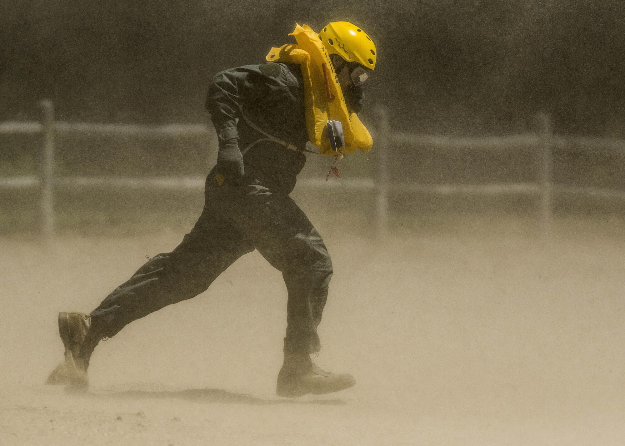 Lt. Col. Brandon Dow, with the 54th Airlift Squadron, runs through the dust kicked up by a UH-60 Blackhawk during Scott's first-ever water extraction training with the 6-101st Aviation Regiment at Lake Carlyle, Ill., June 7, 2017. Dow, Lt. Col. Brooke Matson, with the 375th Operations Support Squadron, and Maj. Madison Basil Jr., with Headquarters Air Mobility Command, received hoist, water survival, and flare training to learn how to survive in aquatic situations long enough to be rescued. The 101st Combat Aviation Brigade has served in almost every single military operation since the Vietnam War, including combat, peacekeeping, and humanitarian. By partnering with Air Mobility Command’s survival, evasion, resistance and escape instructors, this training allows for joint-service coordination while preparing aerial crew members to survive in austere locations after being displaced from their aircraft. (U.S. Air Force photo/Staff Sgt. Jodi Martinez)