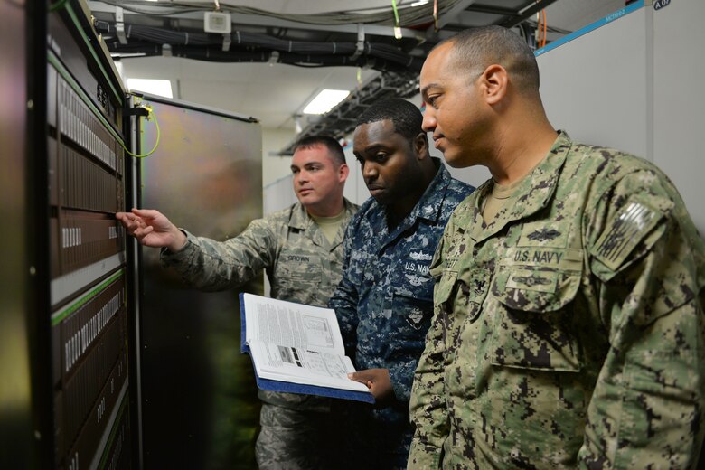 Tech. Sgt. Jonathan Brown, Petty Officers 1st Class Clinton Jordan and Brian Blodgett, 364th Training Squadron Digital Voice Switching course students perform an overview of hardware documentation on the DMS-100 at Sheppard Air Force Base, Texas. This course provides an introduction to major areas of digital switches for identification of telephone exchange switch equipment. (U.S. Air Force photo by Liz H. Colunga/Released)