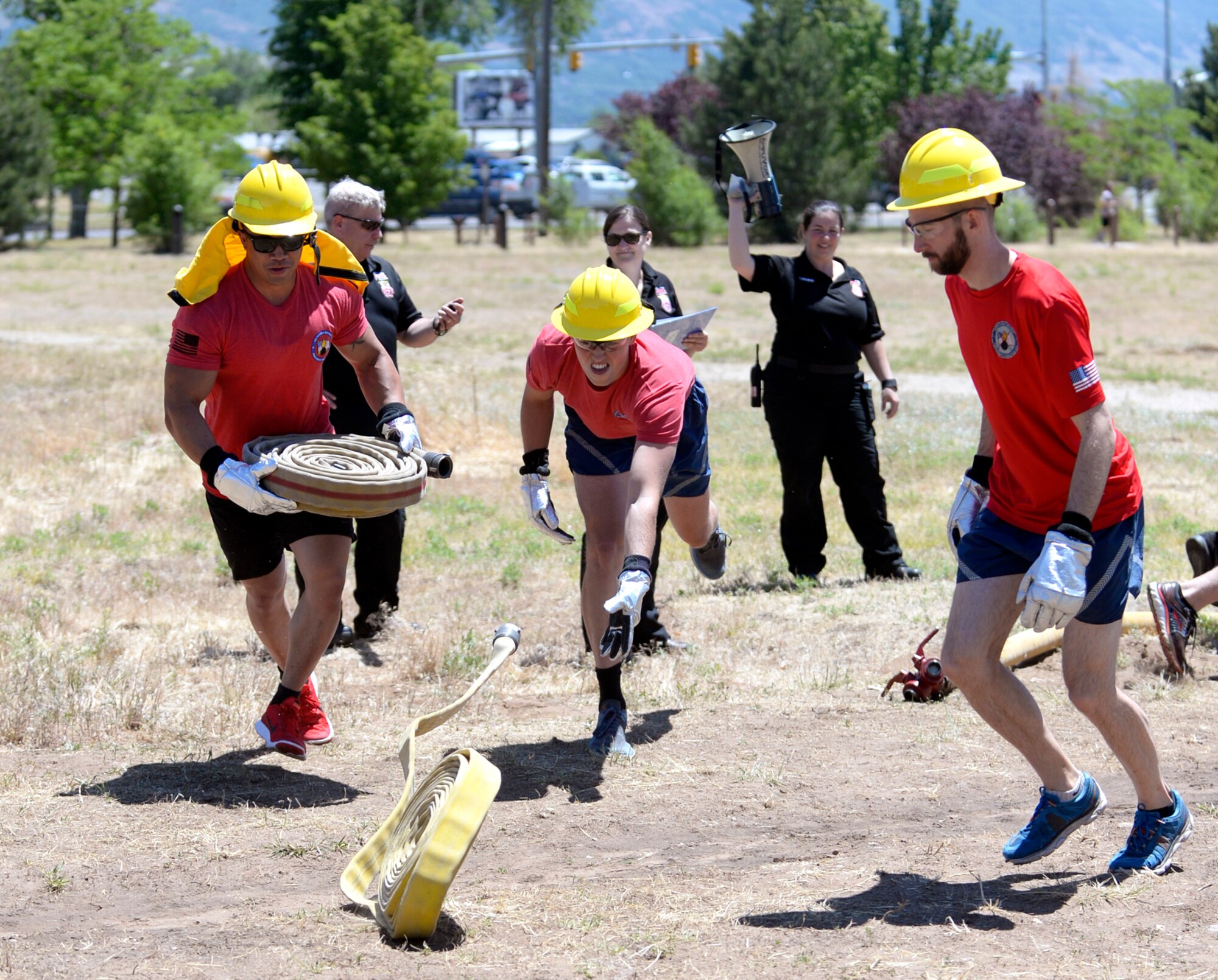 From the left, Staff Sgt. Justin Southichack, 2nd Lt. Caleb Mild and Devin Swanson, all from the ‘Munitions Sustainment Division Team 2’ begin the ‘make or break’ competition where each team must roll out fire hoses, connect a nozzle and use the hose to push a hanging bucket to their opponents side, and then break down and roll up their hose. Teams of Airmen from across the base took part in an annual fire muster, which was held at Centennial Park on Hill Air Force Base, June 14, 2017. (Todd Cromar/U.S. Air Force)
