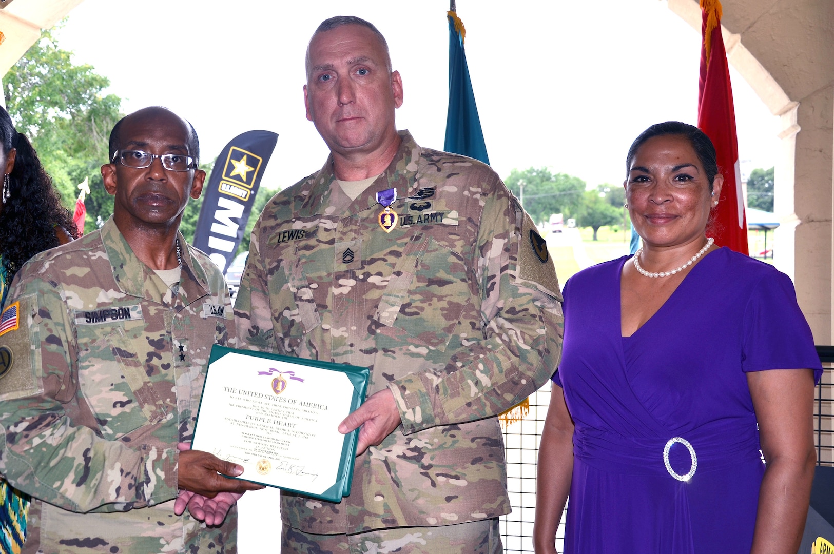 Maj. Gen. James Simpson presents the Purple Heart to Sgt. 1st Class Mark Lewis June 9 at Joint Base San Antonio-Fort Sam Houston, Texas. Simpson is the Army Contracting Command commanding general, and Lewis is a contracting specialist assigned to Field Directorate Office-Fort Sam Houston. Also pictured is Lewis’ wife, Belinda.