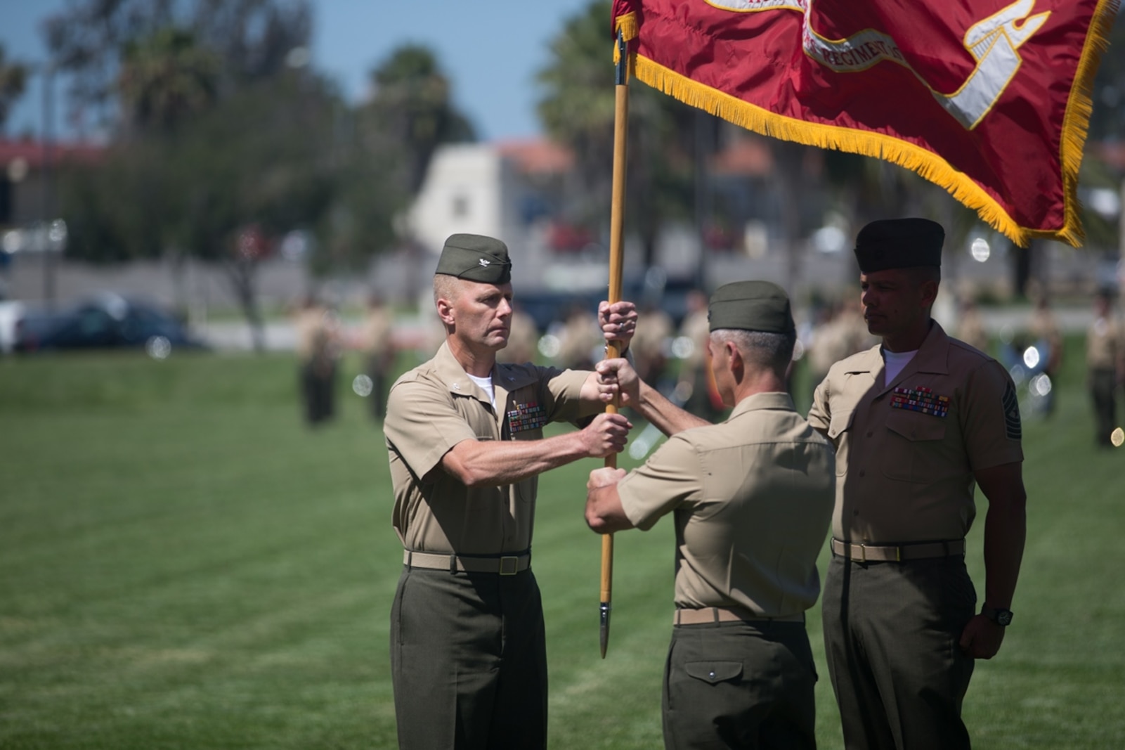 U.S. Marine Col. Phillip N. Frietze (center) exchanges the regimental colors with Col. James R. Hensein (left) during the Headquarters Regiment, 1st Marine Logistics Group, change of command ceremony on Camp Pendleton, Calif., June 15, 2017. The ceremony included marching of the colors, passing of the regimental colors, presenting Col. Frietze his away and closing remarks from the oncoming and off going personnel as well as the 1st Marine Logistics Group Commanding General, Brig. Gen. David A. Ottignon. (U.S. Marine Corps photo by Lance Cpl. Timothy Shoemaker)