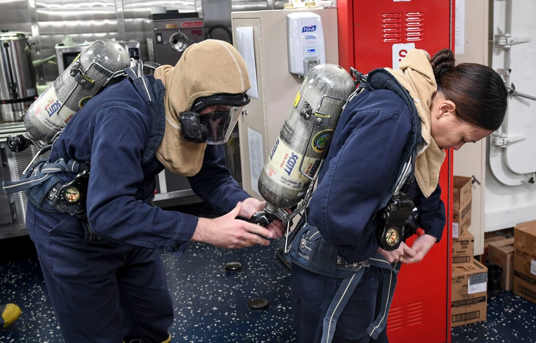 Navy Petty Officer 3rd Class Cody Parrish, left, and Petty Officer 1st Class Sandi Anteola, prepare firefighting gear during an integrated training team drill aboard the guided-missile destroyer USS Wayne E. Meyer in the Western Pacific Ocean, June 8, 2017. The ship is on a regularly scheduled Western Pacific deployment with the Carl Vinson Carrier Strike Group as part of the U.S. Pacific Fleet-led initiative to extend U.S. 3rd Fleet command and control functions into the Indo-Asia-Pacific region. Navy photo by Petty Officer 3rd Class Kelsey L. Adams