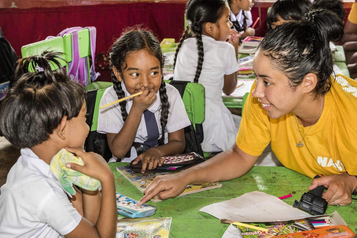 A sailor talks with students during a community engagement event.