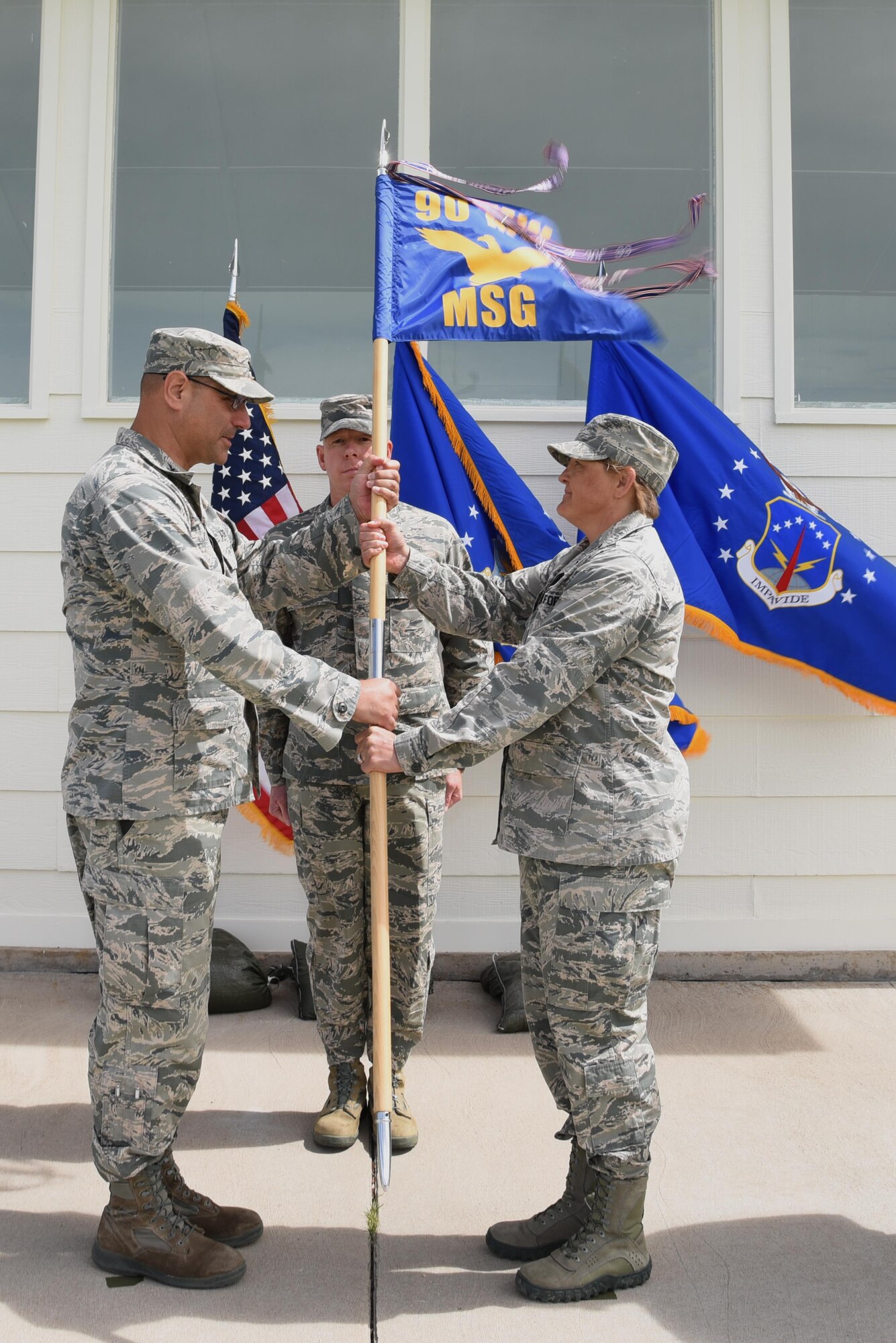 Colonel Stephen Kravitsky, 90th Missile Wing commander, passes the guidon to Col. Tricia Van Den Top, 90th Mission Support Group commander, during the 90th MSG Change of Command ceremony June 16, 2017, on the Argonne Parade Field at F.E. Warren Air Force Base, Wyo. The ceremony signified the transition of command from Col. Frank Verdugo to Van Den Top. (U.S. Air Force photo by Glenn S. Robertson)