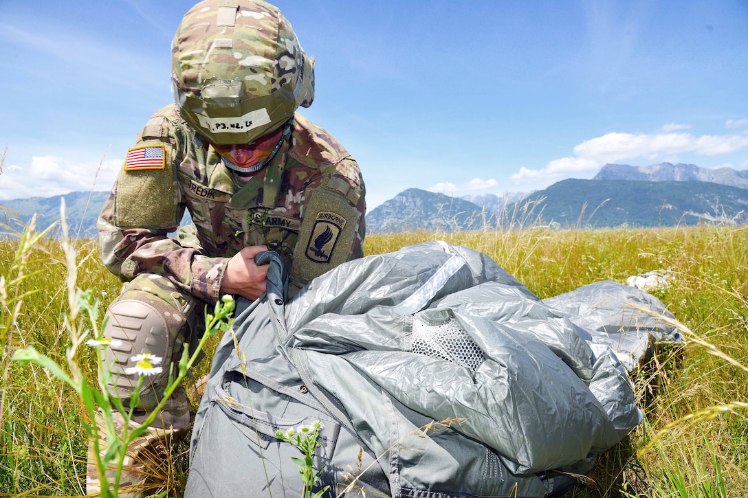 Army Pvt. Mason Tredik recovers his equipment after a jump at the Juliet Drop Zone in Pordenone, Italy, June 8, 2017. 