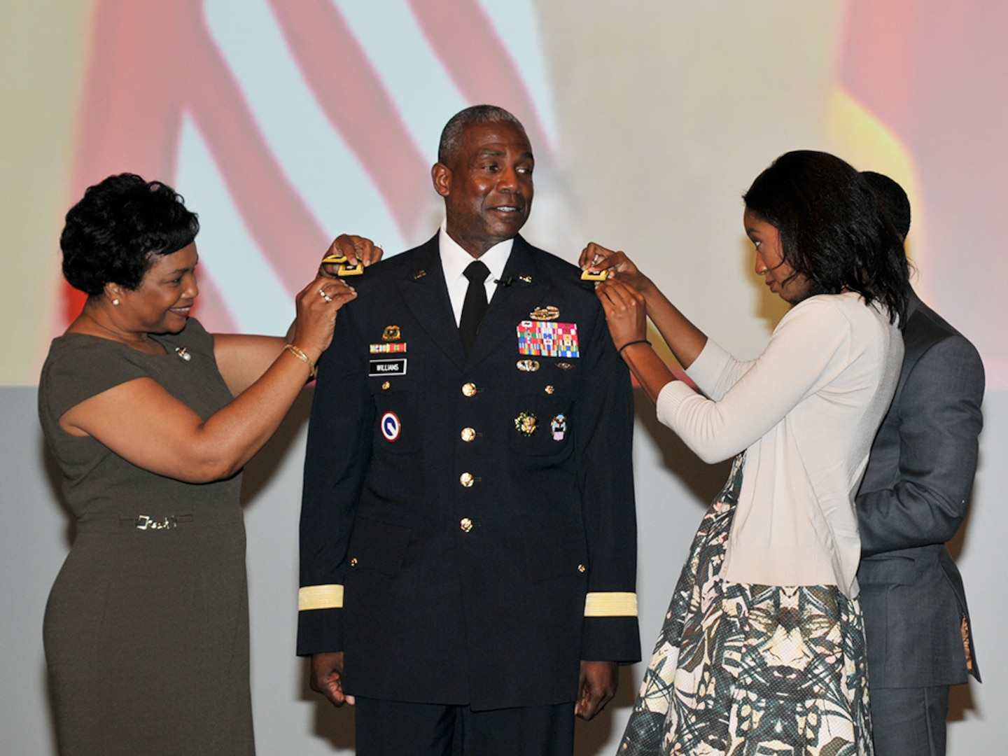 DLA Director Army Lt. Gen. Darrell Williams receives his three-star shoulder boards from (left-right) his wife Myra and his children.