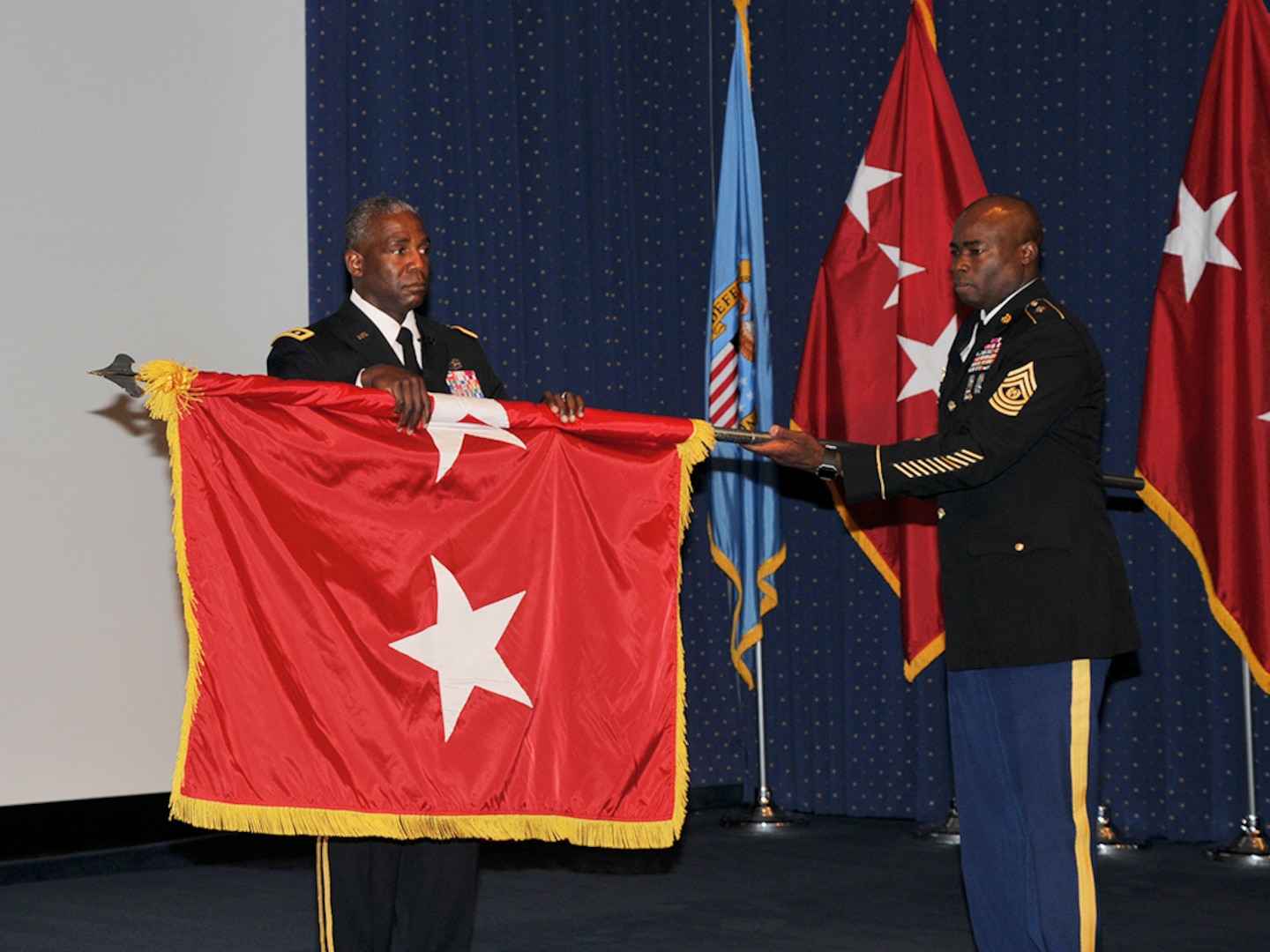 DLA Director Army Lt. Gen. Darrell Williams (left) and Command Sgt. Maj. Nathaniel Bartee, senior enlisted leader of the Army Combined Arms Support Command, unfurl Williams' three-star flag.